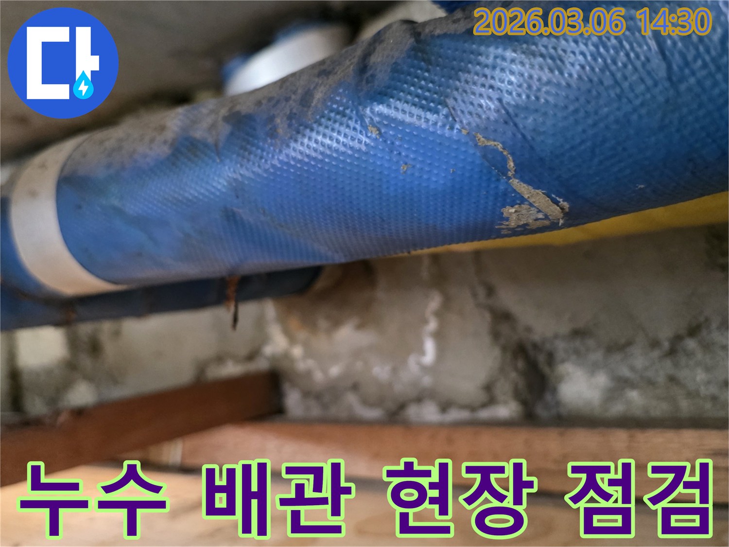 오래된 건물 내부-파란색 배관과-젖은 콘크리트 벽면-그리고 나무 지지대를-정밀하게 점검하는 모습