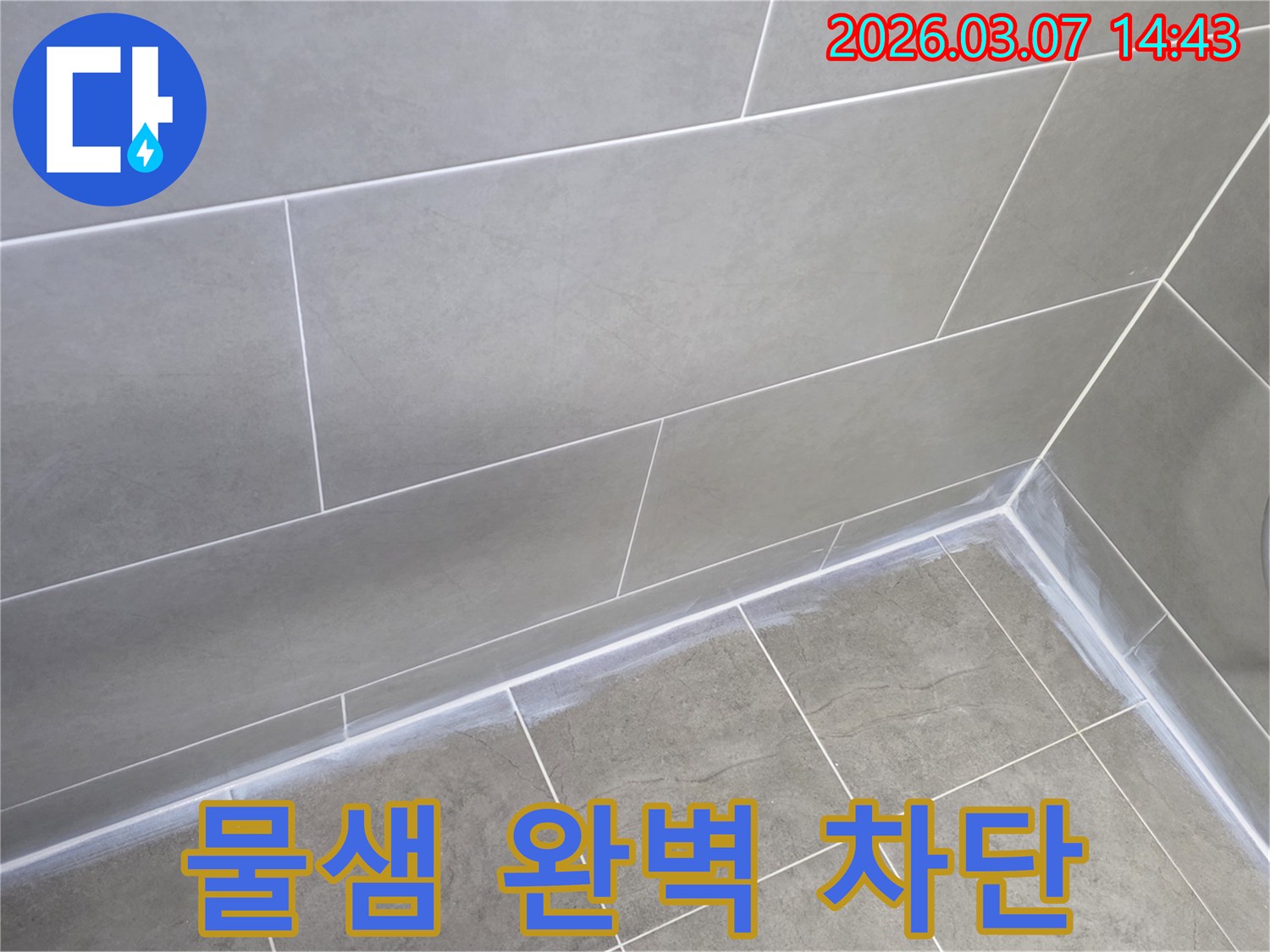 회색 타일로 마감된-주택 욕실의-벽과 바닥 이음새를-새로운 실리콘으로-빈틈없이 밀봉하여-물샘을 완벽히 차단한 모습