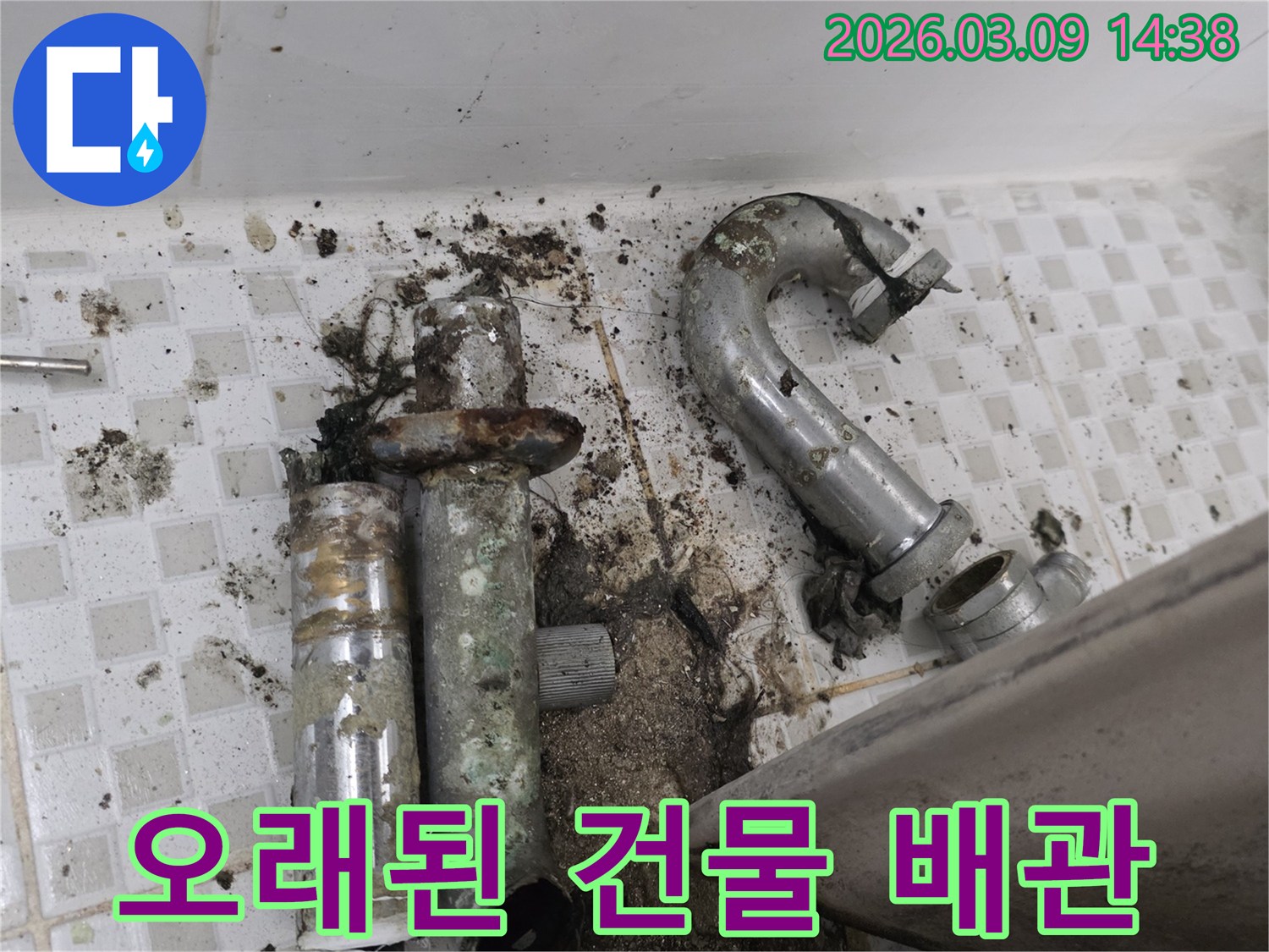 이 이미지는 공릉동 오래된 건물에서 발견된-심하게 노후되어 파손된 배관과-그로 인해 오염된 바닥을 보여줍니다-누수 공사 전의 상태입니다