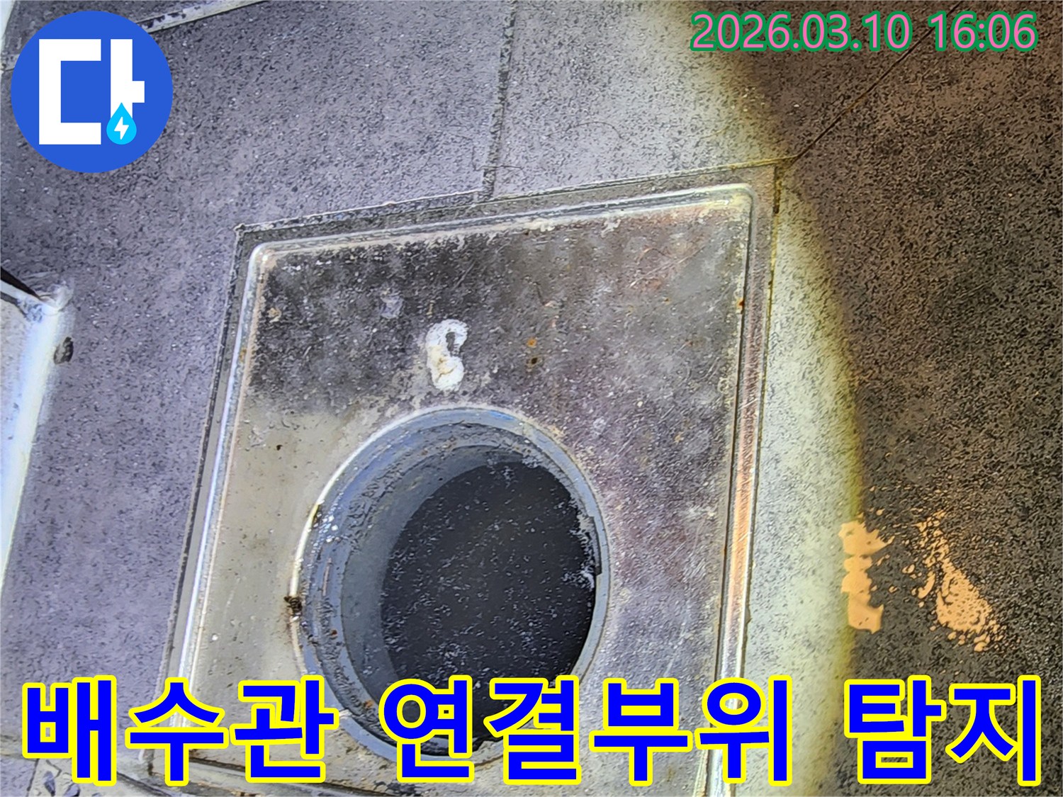 이 이미지는-서울 중구의 한 빌라에서-배수관 연결 부위의-미세 누수를 탐지하기 위해-배수구 내부를-정밀하게 점검하는-현장을 포착한 것입니다