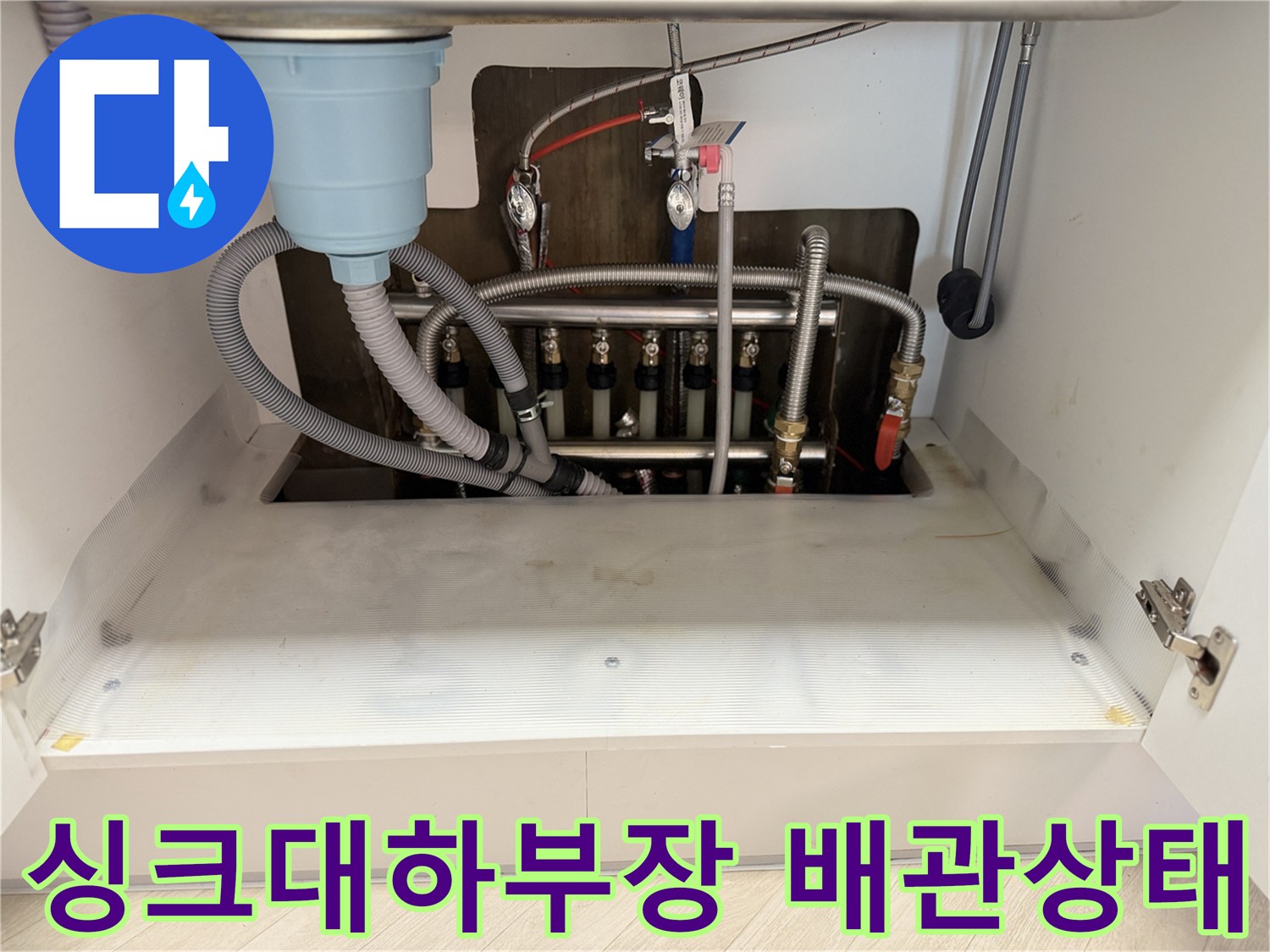 싱크대 하부장 내부-노후된 난방 분배기와 배관 연결 부위 모습