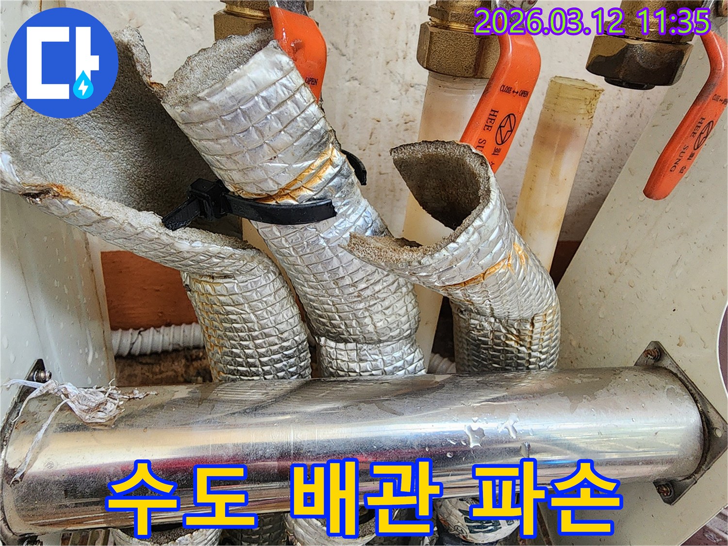 보온재가 파손되고-물방울이 맺힌-수도 배관의 누수 흔적을 보여주는-현장 사진입니다.