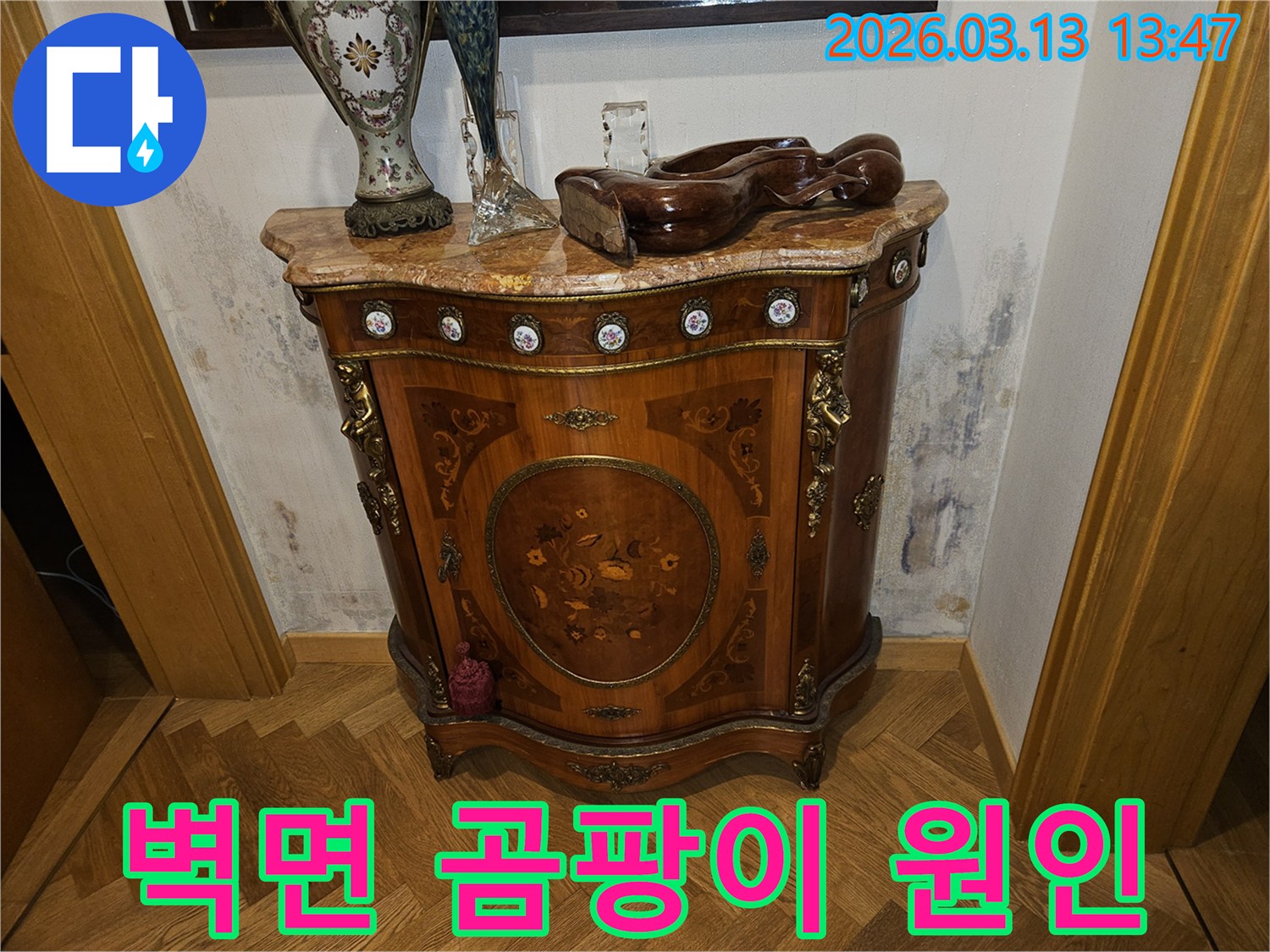 고급스러운 콘솔 가구 뒤-벽에 발생한-누수로 인한-벽지 변색과-곰팡이 흔적을 보여주는 사진