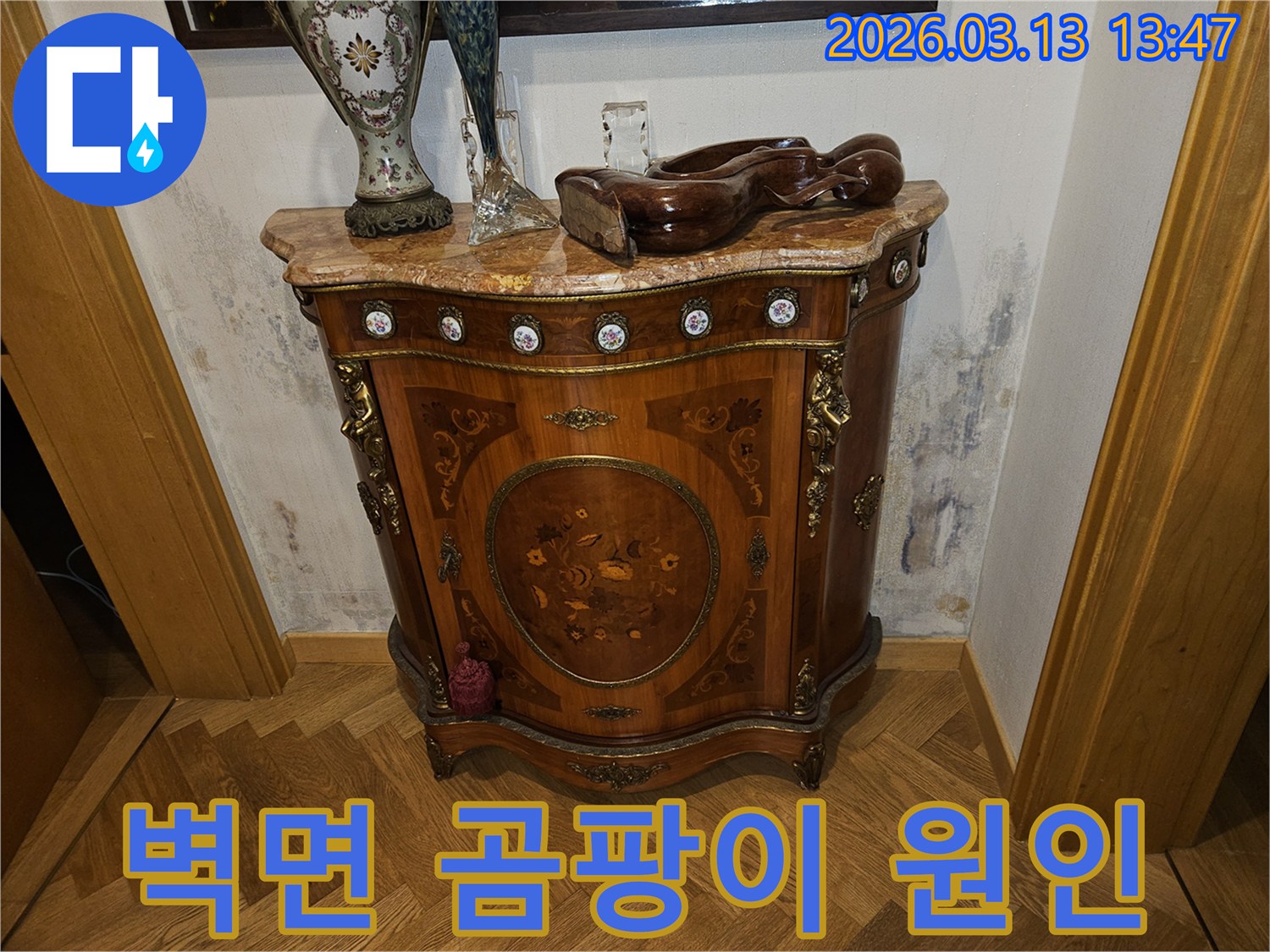 고급스러운 콘솔 가구 뒤-벽에 발생한-누수로 인한-벽지 변색과-곰팡이 흔적을 보여주는 사진