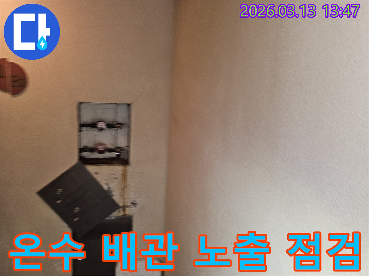 아파트 누수 해결을 위해-벽면을 절개하고-노출된 온수 배관을 점검하는 모습입니다