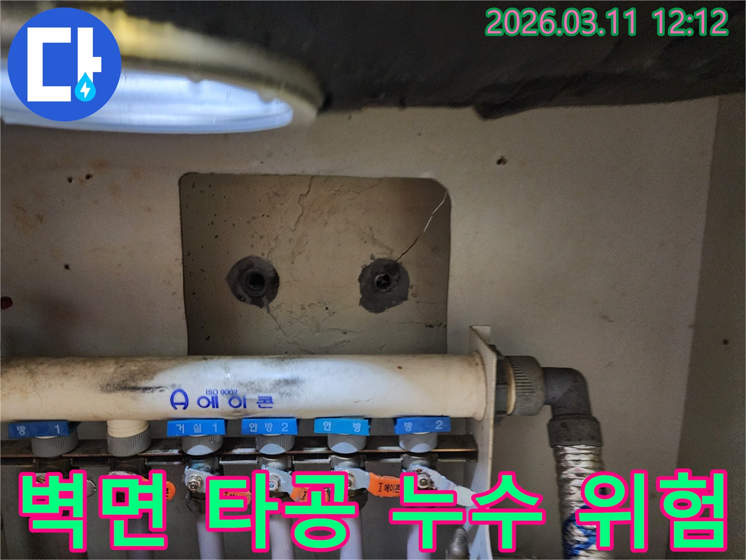 보일러 분배기 상단-벽면에 있는-타공 부위 주변을-누수 위험 요소로-점검하는-누수 전문가의-작업 현장