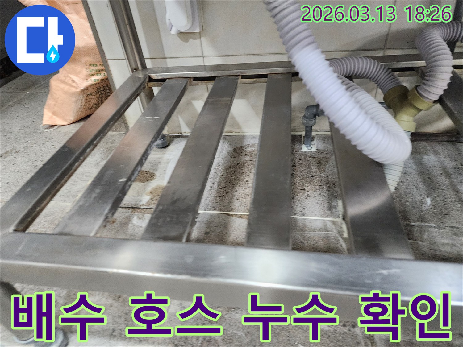 누수-발생 현장에서-배수 호스의-연결 부위와-주변 바닥의-습기 상태를-꼼꼼하게 확인하는 모습