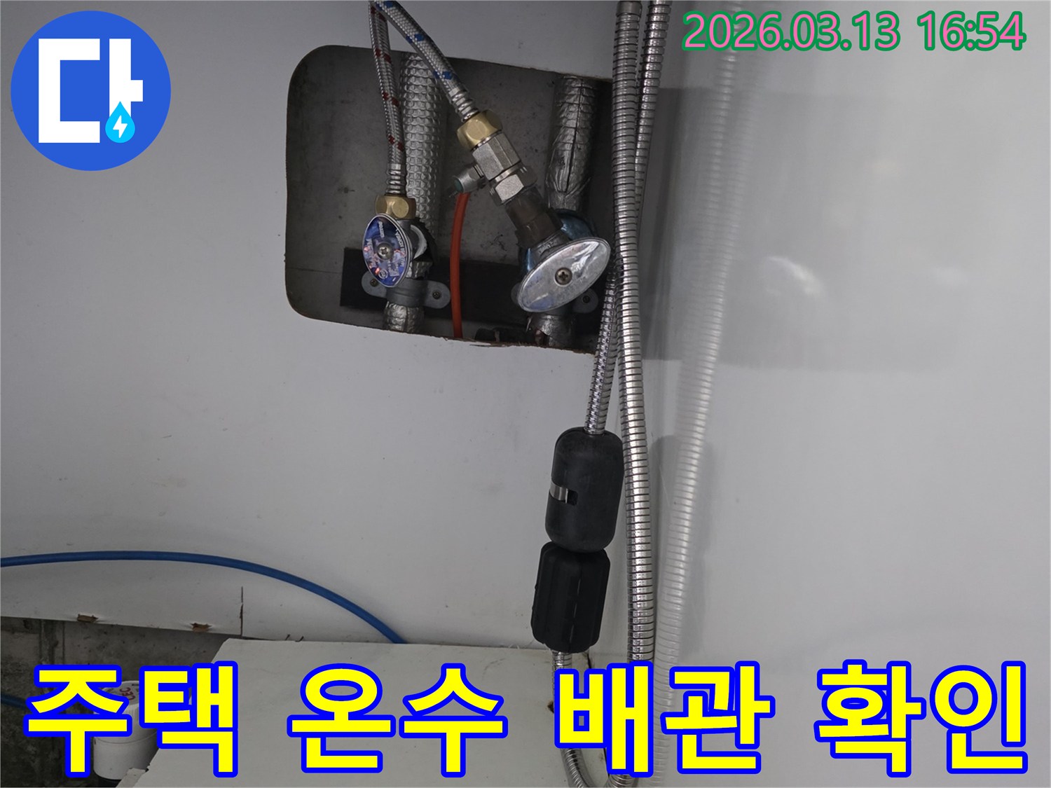 이 사진은 주택 내부-온수 배관의 밸브와 연결 호스를 보여줍니다.