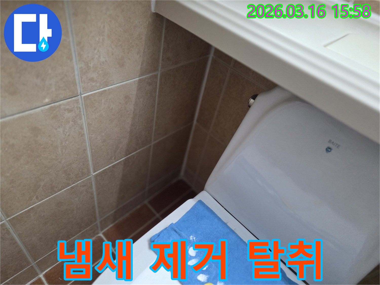 오산시 운암동의-한 욕실에서-변기 뒤편-벽면 타일의 젖음으로-누수 수리 후-냄새 제거 및-탈취 작업을-진행하는 현장을-보여주는 사진입니다.