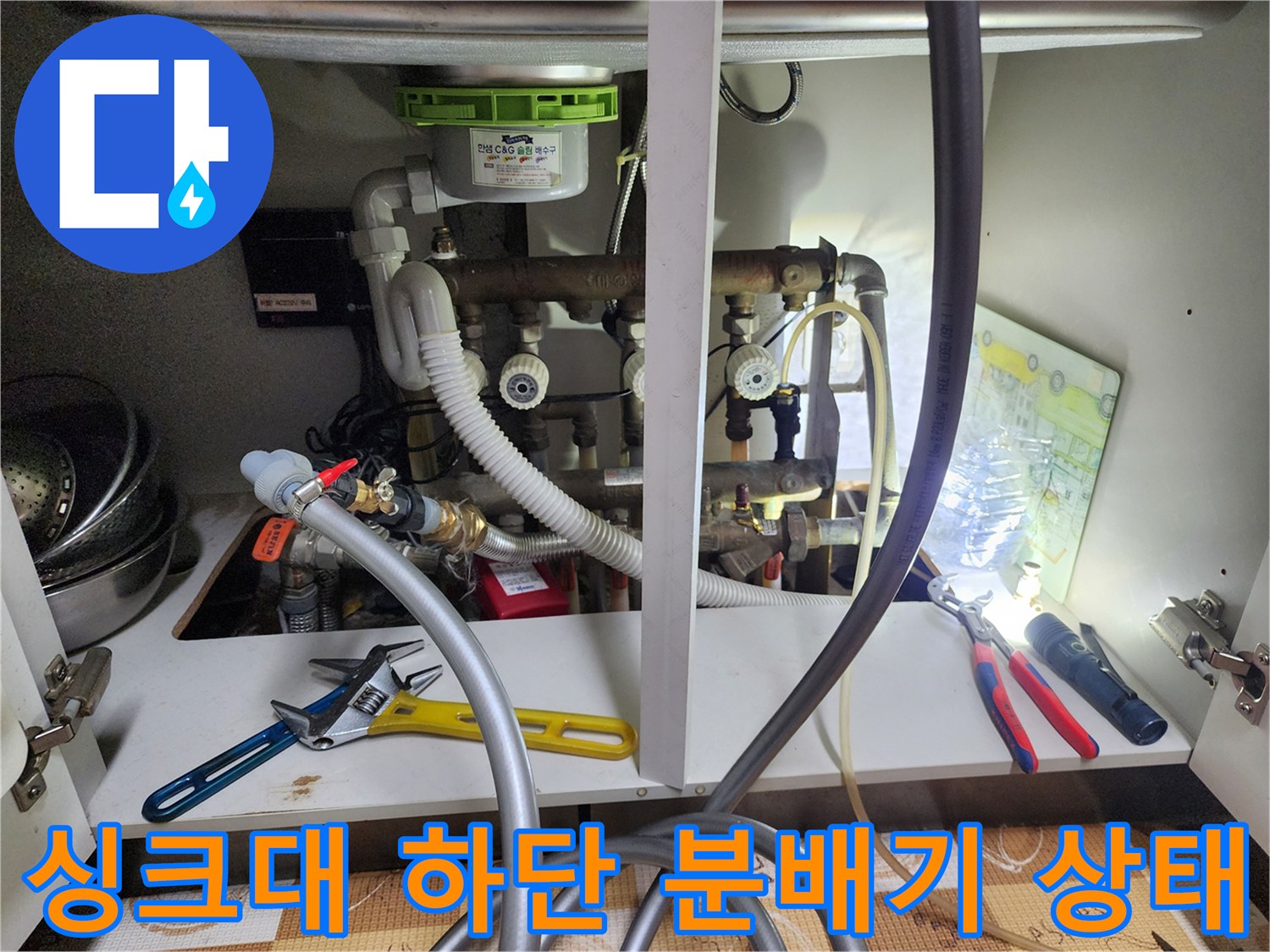 싱크대-하부장-내부의-복잡한-난방-분배기-및-배관-연결-상태
