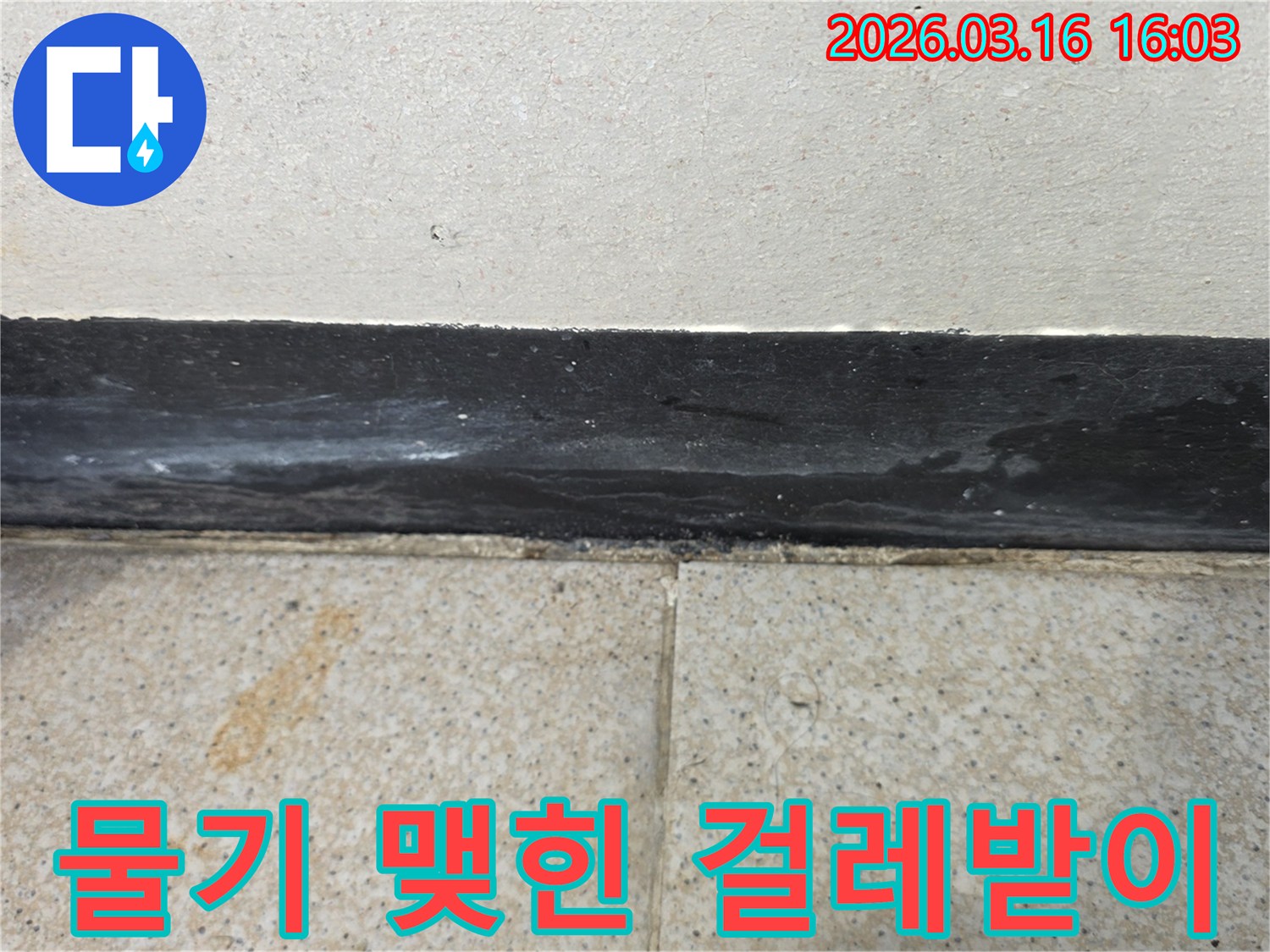 걸레받이 표면에 물기가 맺혀 있고 주변 타일에도 얼룩이 보여 누수가 의심됩니다