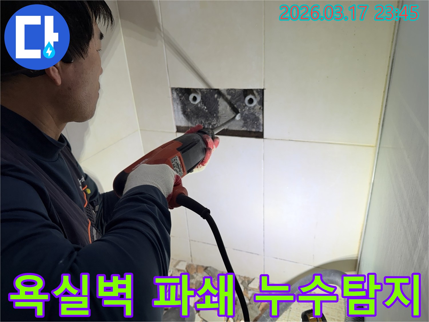 누수 공사 전문가가 욕실 벽면의 타일을 조심스럽게 파쇄하여-누수 원인을 찾기 위한 배관 확인 작업을 진행하는 모습입니다.