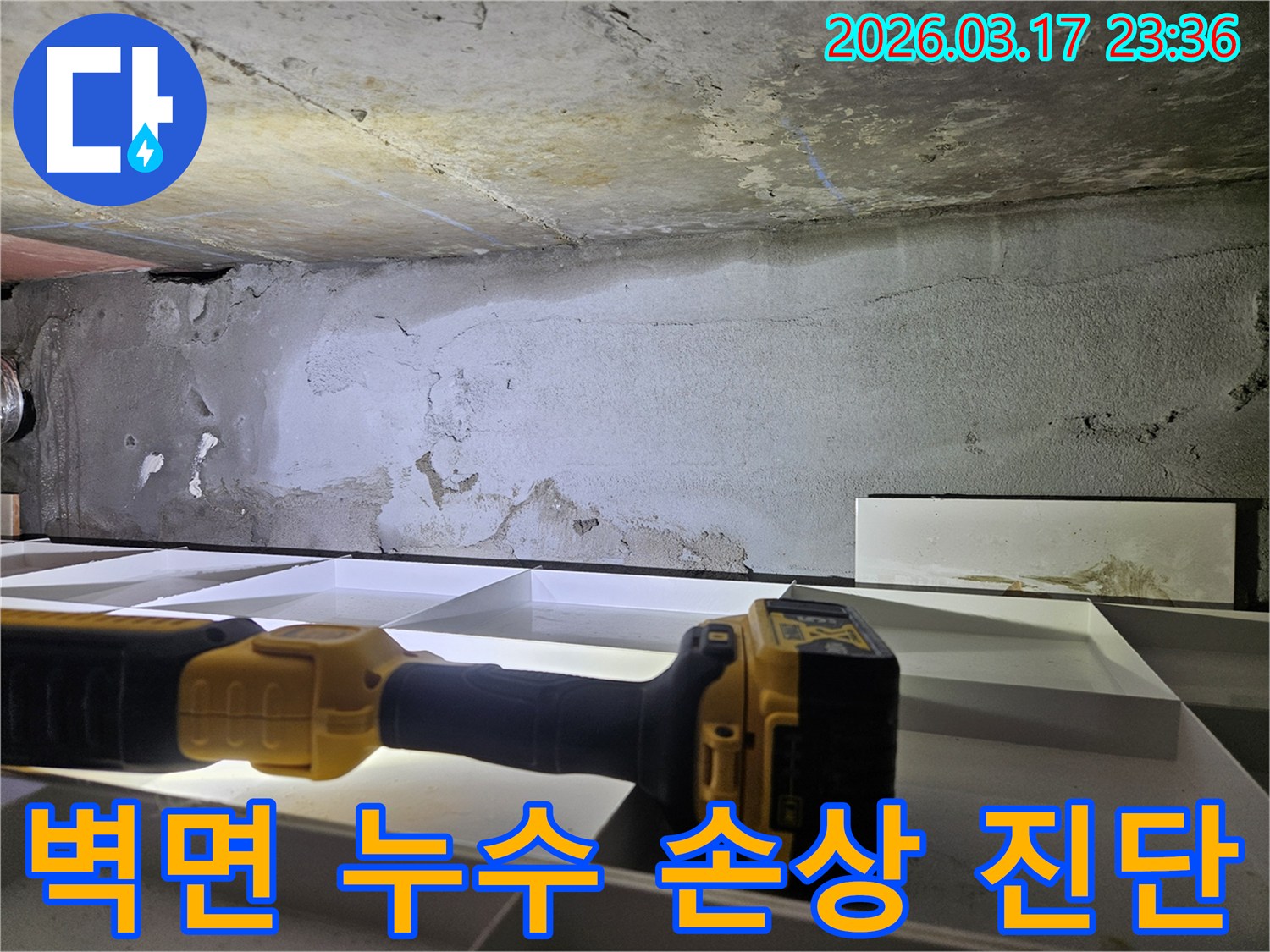 누수 전문 엔지니어가-플래시로 천장 벽면의-페인트 벗겨짐과 변색 등-누수로 인한 손상 부위를-세밀하게 진단하고 있습니다.