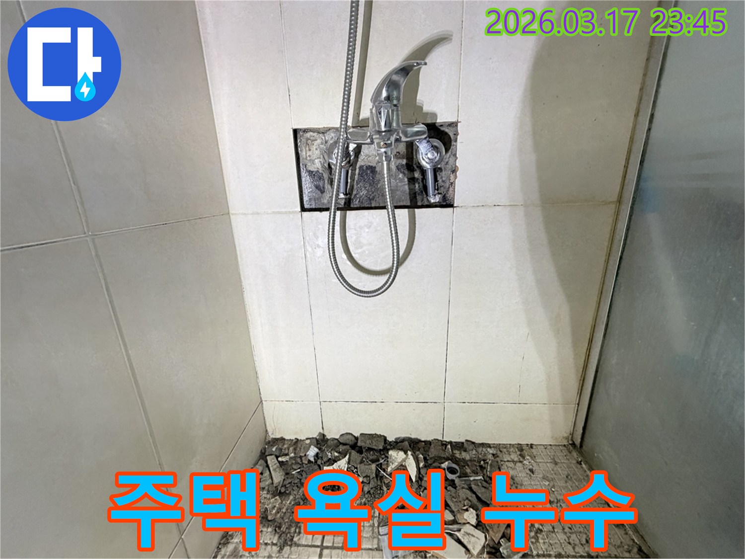 누수가 발생한 화성 병점 주택의 욕실에서-샤워 수전이 제거되고-바닥 타일이 파손된 채로-배관 점검이 진행 중인 모습입니다.