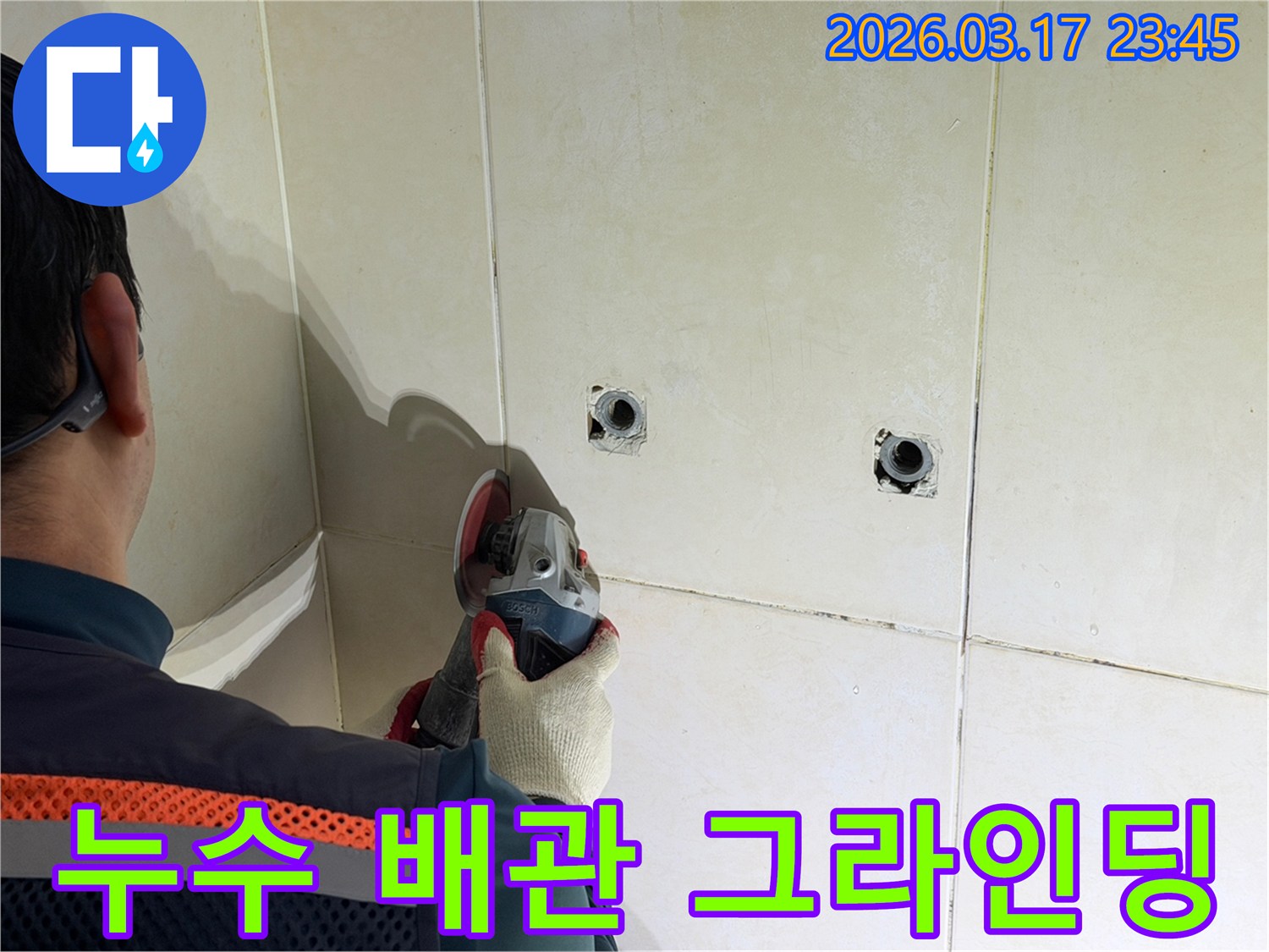누수된 배관을-노출시키기 위해-전문가가-타일 벽면을-그라인더로-조심스럽게-그라인딩하고-있습니다
