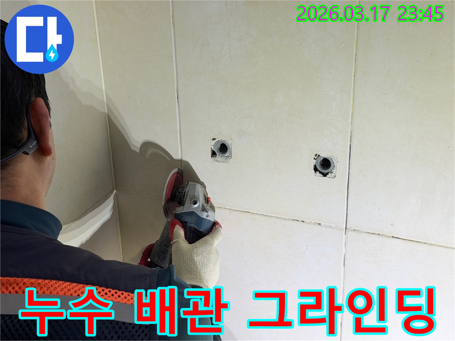 누수된 배관을-노출시키기 위해-전문가가-타일 벽면을-그라인더로-조심스럽게-그라인딩하고-있습니다