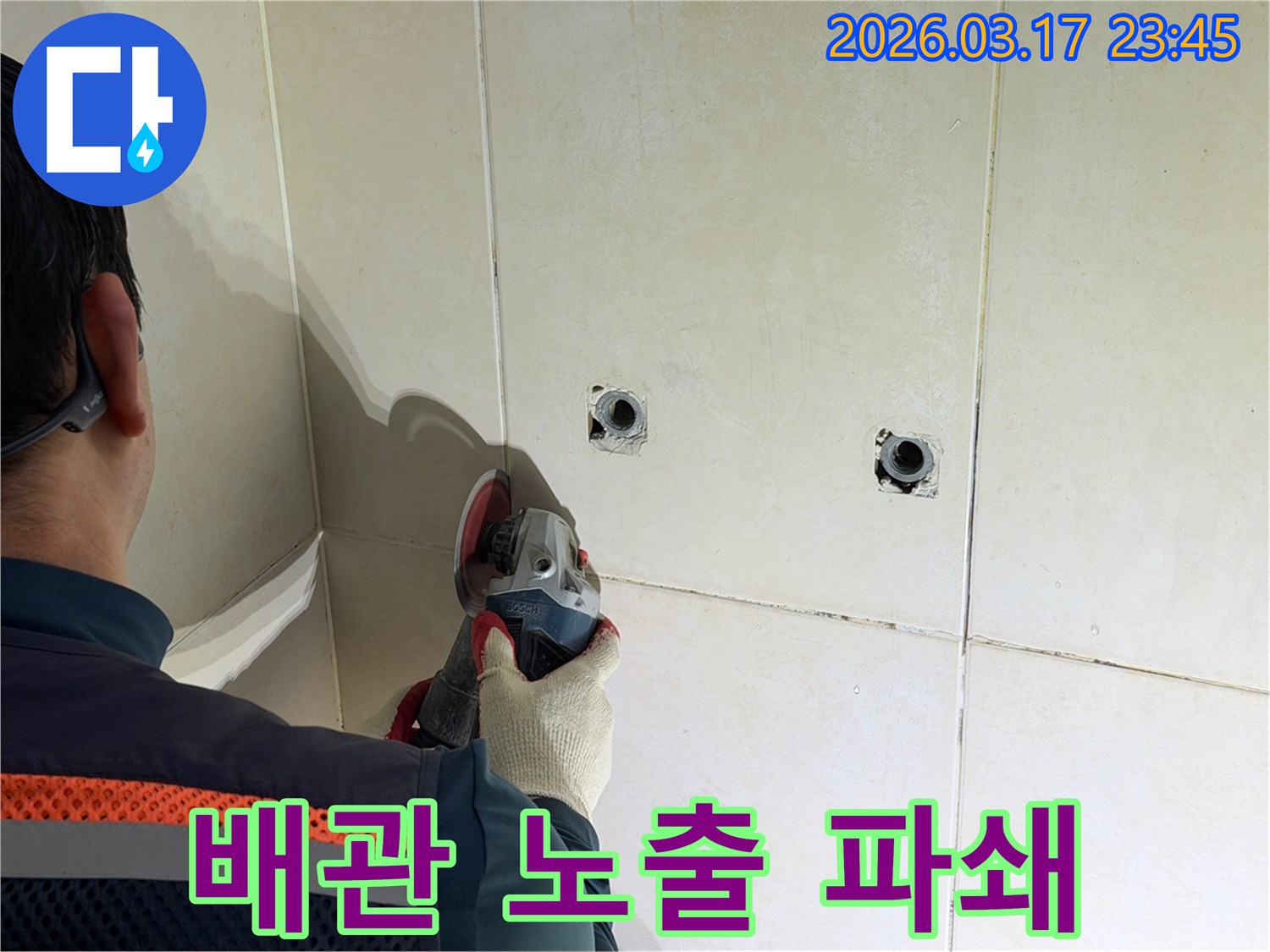 누수된 배관을-노출시키기 위해-전문가가-타일 벽면을-그라인더로-조심스럽게-파쇄하고-있습니다
