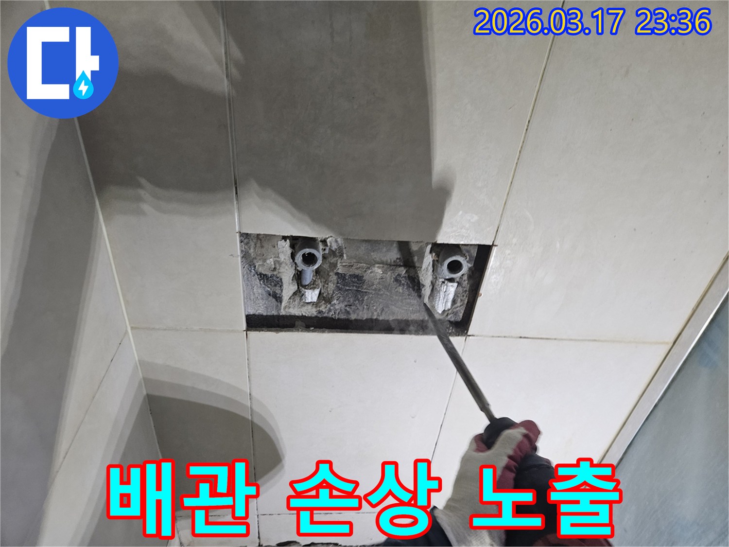 누수탐지-전문가가-욕실 벽면 타일을-조심스럽게 파쇄하여-배관 손상 부위를-노출하는 모습