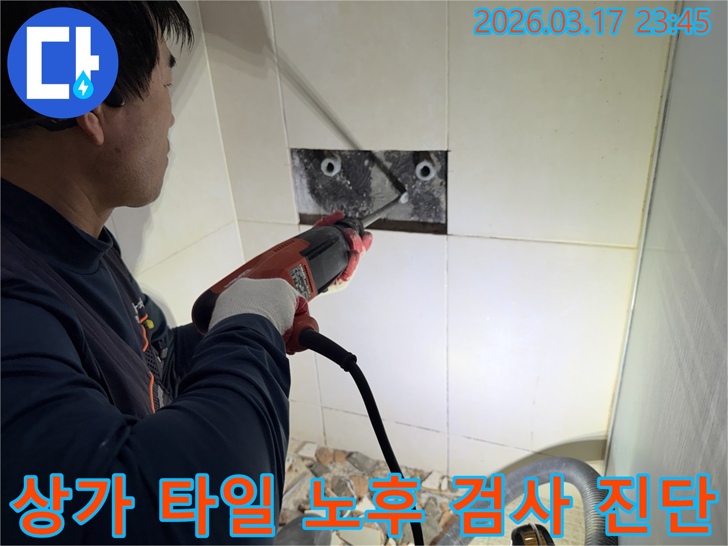 숙련된 기술자가 상가 누수 지점을 찾아내기 위해-벽면 타일을 깨고 내부 배관의 노후화 여부를 육안으로 검사하고 진단하는 작업을 진행하고 있습니다.