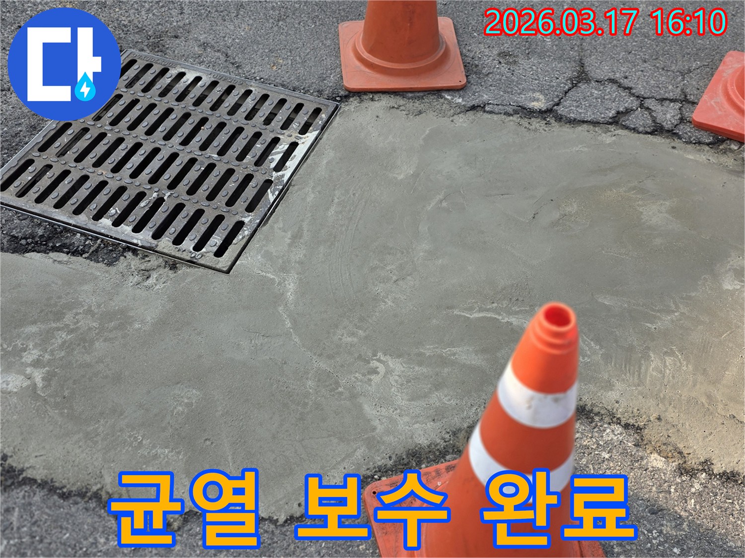이 이미지는 경기 양주 지역의 외부 배수구 주변 균열 누수 보수 작업이 완료된 상태를 보여주며-새로운 시멘트 마감과 안전 콘이 놓여 있습니다.