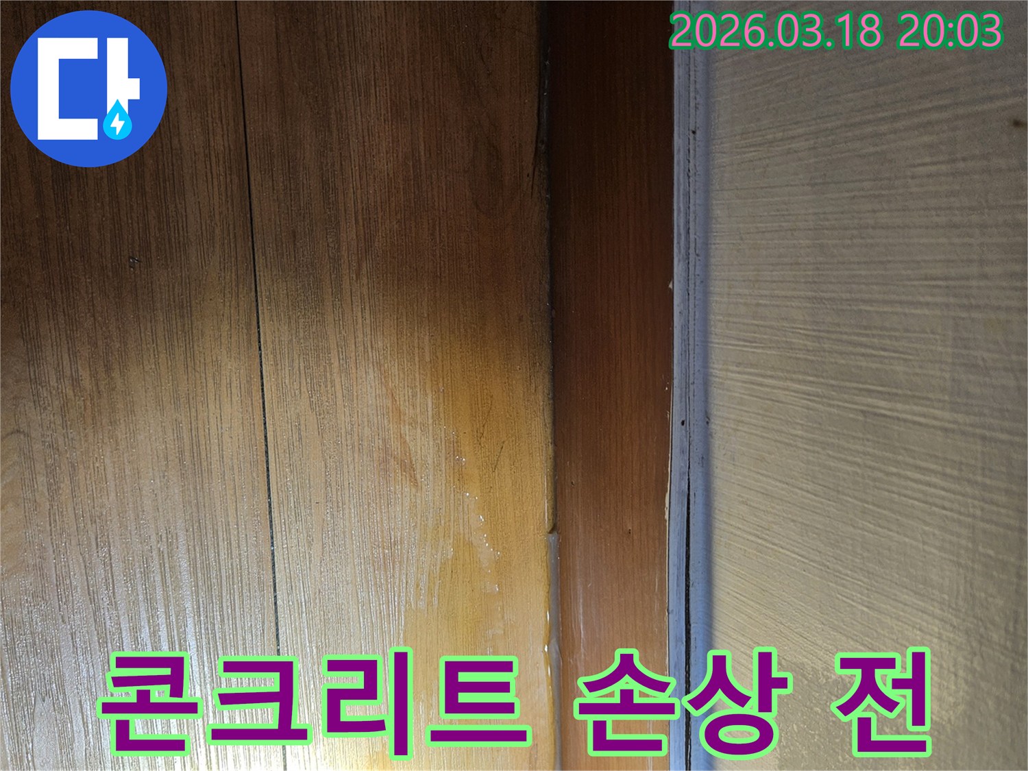 벽면 몰딩 아래-나무 바닥에 물기가-스며들어 변색된 모습은-하부 콘크리트 구조물에-습기가 침투하여-손상될 위험이 있는-누수 현장입니다.