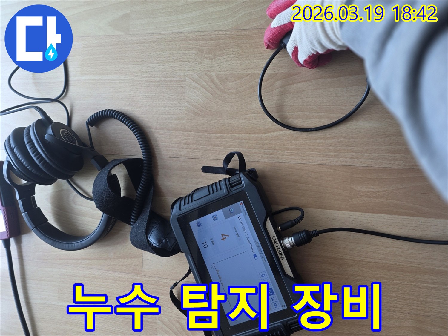 전문가가-누수 탐지 장비와 헤드폰을 사용하여-바닥에서 발생하는-미세한 누수 소리를-집중적으로 듣고 분석하는 장면입니다