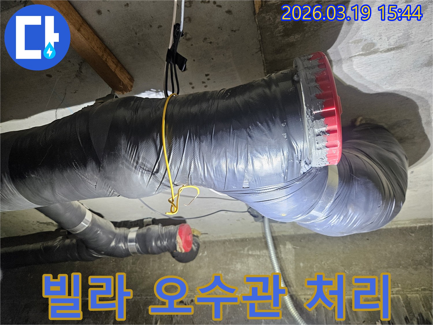 천장에 설치된 검은색 단열재로 감싸진 굵은 오수관과-그 옆으로 연결된 회색 파이프들이 보입니다