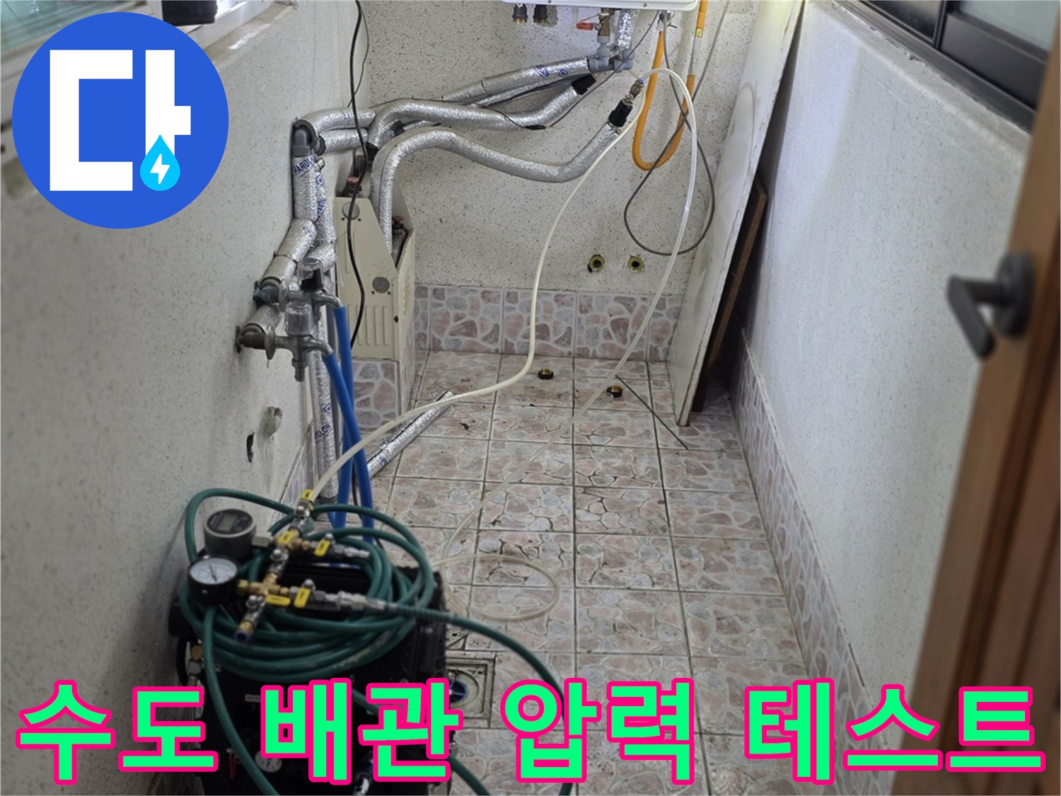 타일 벽면에 설치된 보일러 배관과 연결된 수압 측정 장비 이미지
