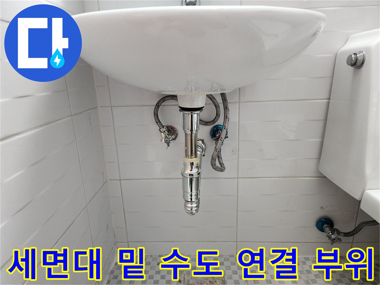 세면대 하단 벽면에 위치한 배관과 밸브의 모습입니다.