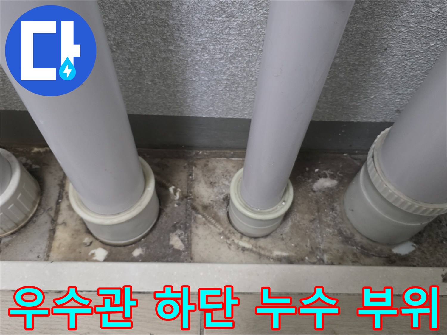 배관 주변의 젖은 타일과 노후된 배수관 연결부 모습