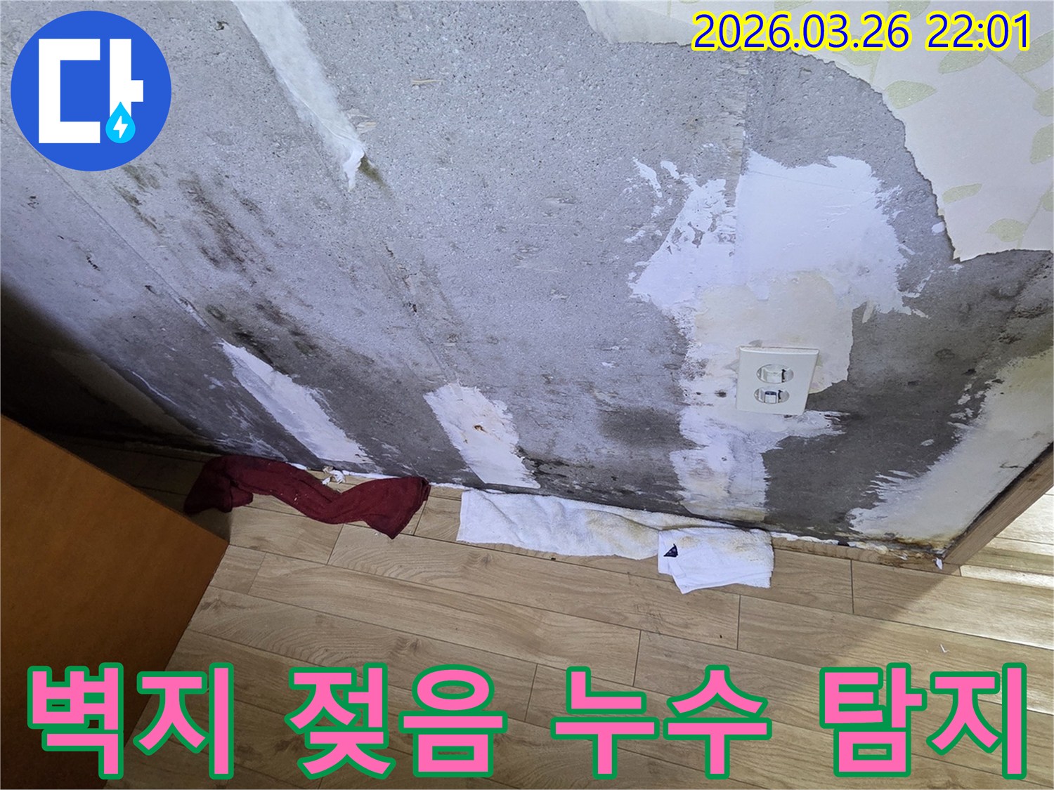 벽지가-젖어-탈락하고-얼룩진-콘크리트-벽면-아래-물기를-흡수하는-수건이-놓여있는-누수-현장-사진