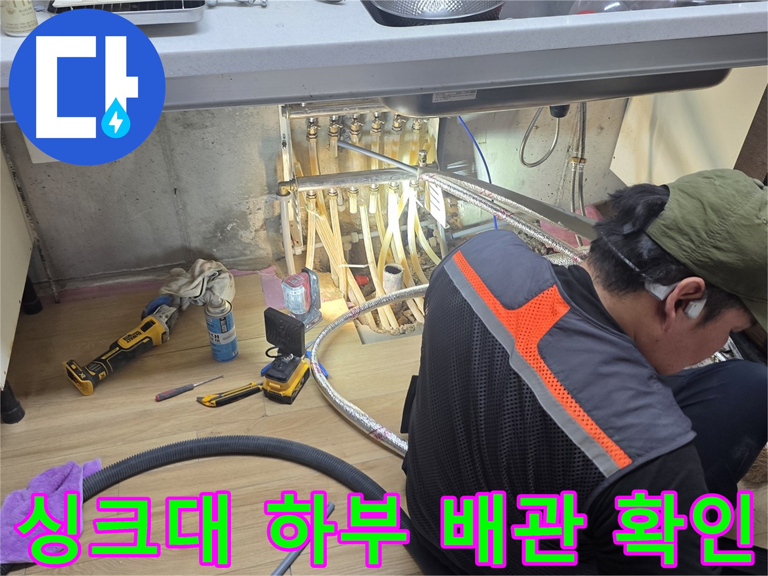싱크대 아래 복잡한 배관들을 점검하고 있는 전문가의 모습