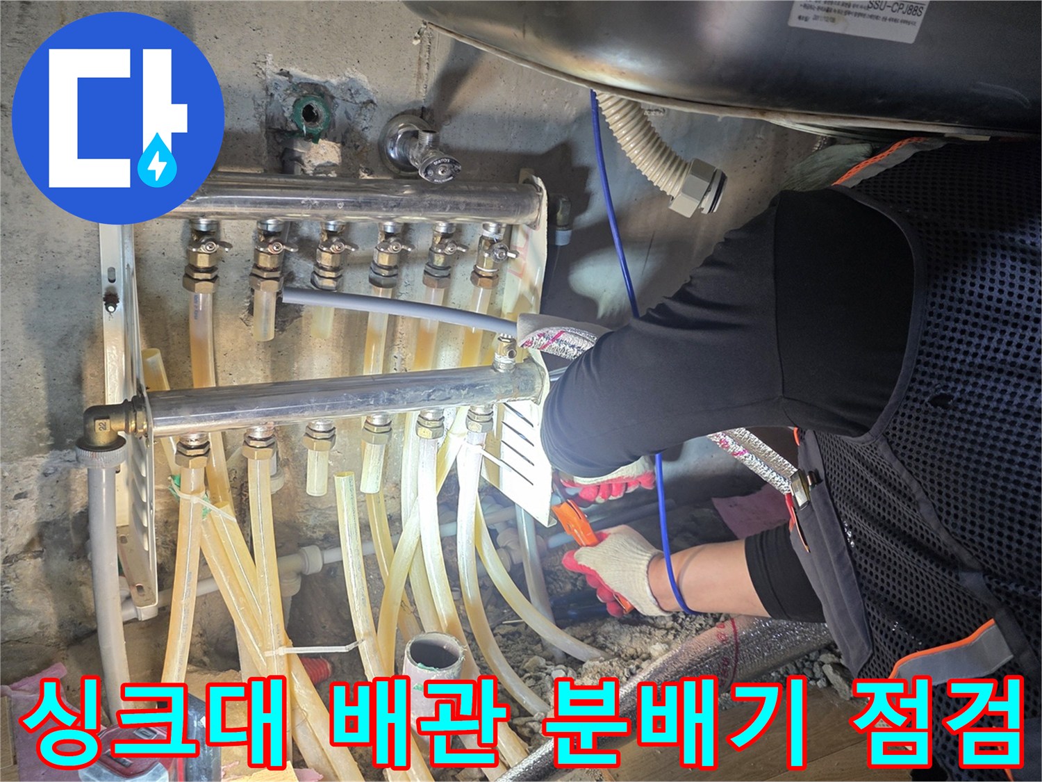 싱크대 하부장 내부의 수도 분배기와 연결된 배관 상태를 확인하는 모습