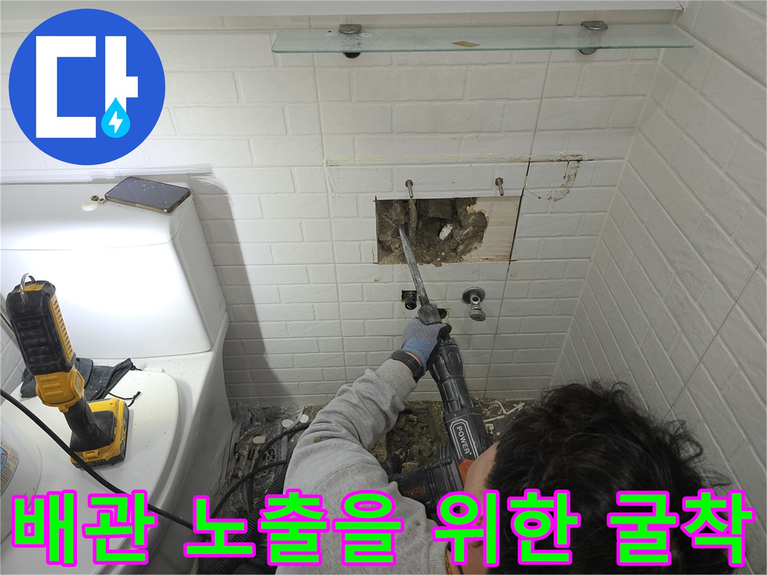 세면대 뒤쪽 타일을 제거하고 내부 배관 확인을 위해 콘크리트 벽면을 파내는 작업 현장
