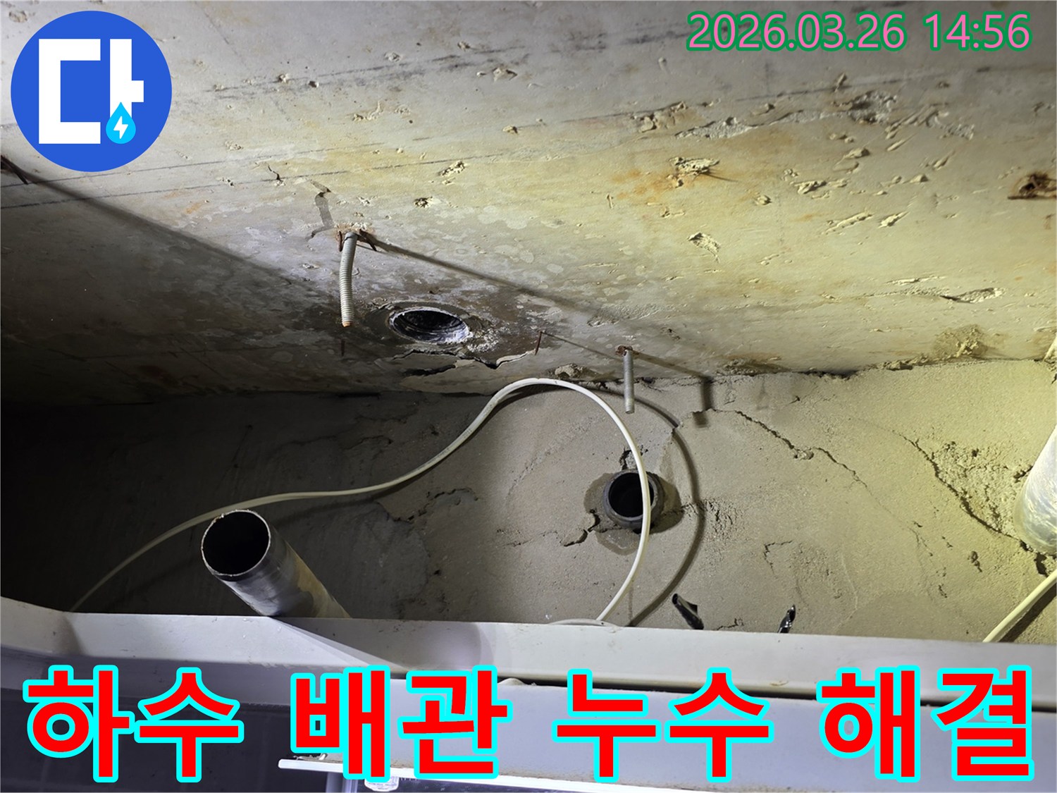 이 이미지는-천장에 노출된 하수 배관에서-발생한 누수 문제를-전문가가 해결하는-공사 현장을 보여줍니다.