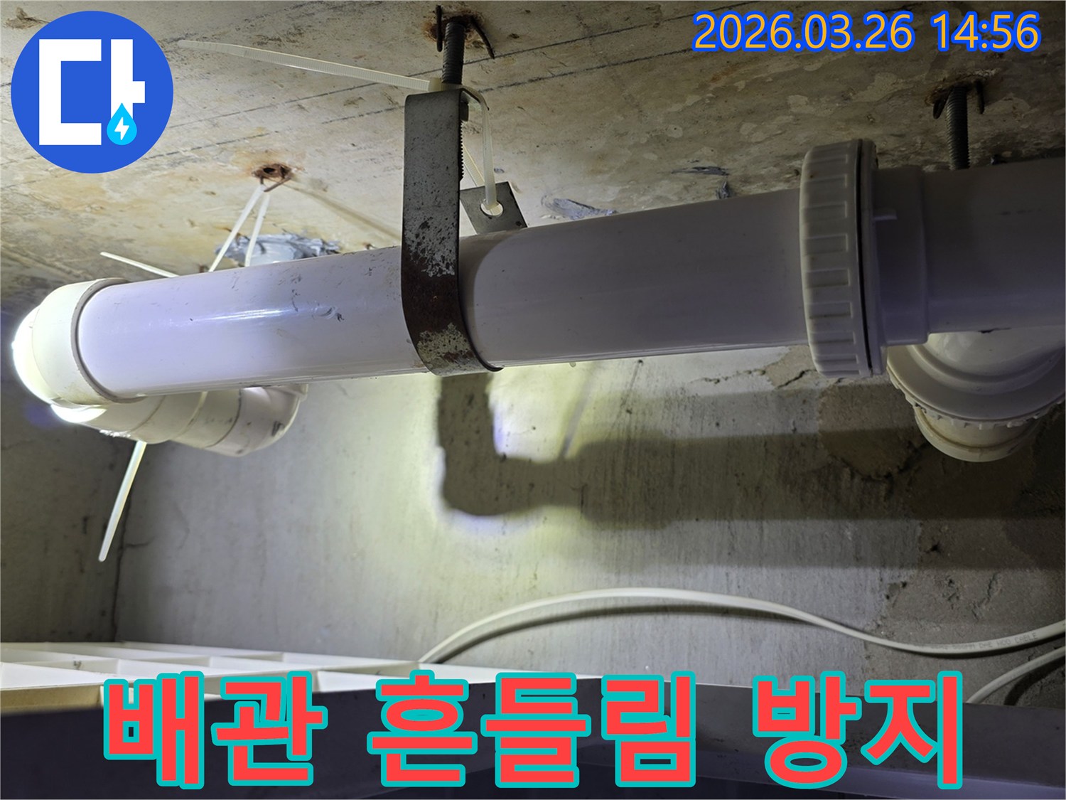 콘크리트 천장에 고정된-하얀색 배관과-오래된 금속 지지대의 모습으로-배관 흔들림 방지 보강 작업을 보여줍니다