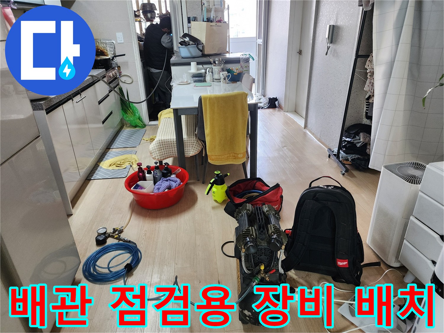누수 지점을 찾기 위해 거실 바닥에 배치된 블루 호스와 공압 측정 기기
