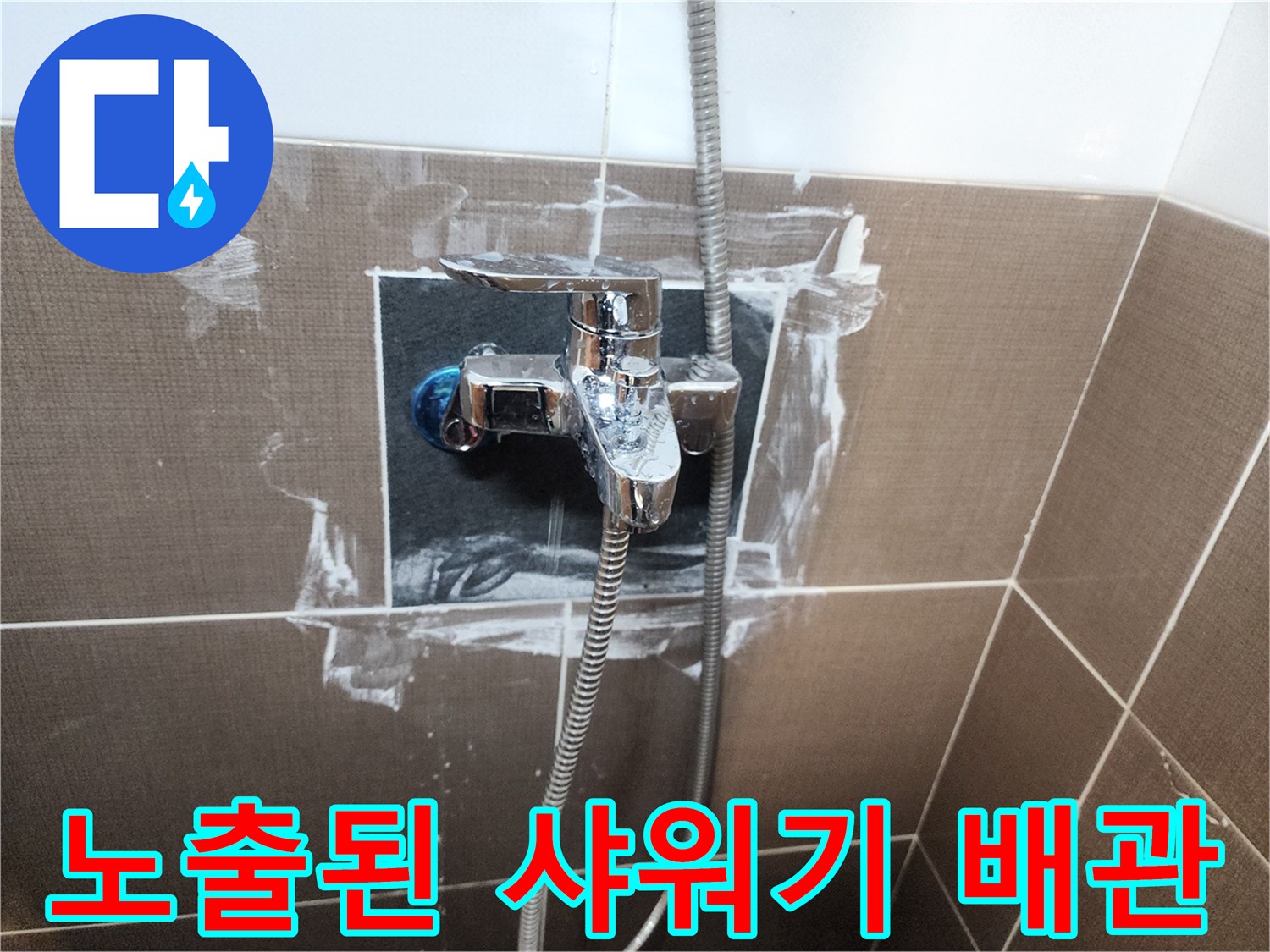 타일이 제거된 벽면 아래로 보이는 샤워 수전과 배관 연결 부위입니다.