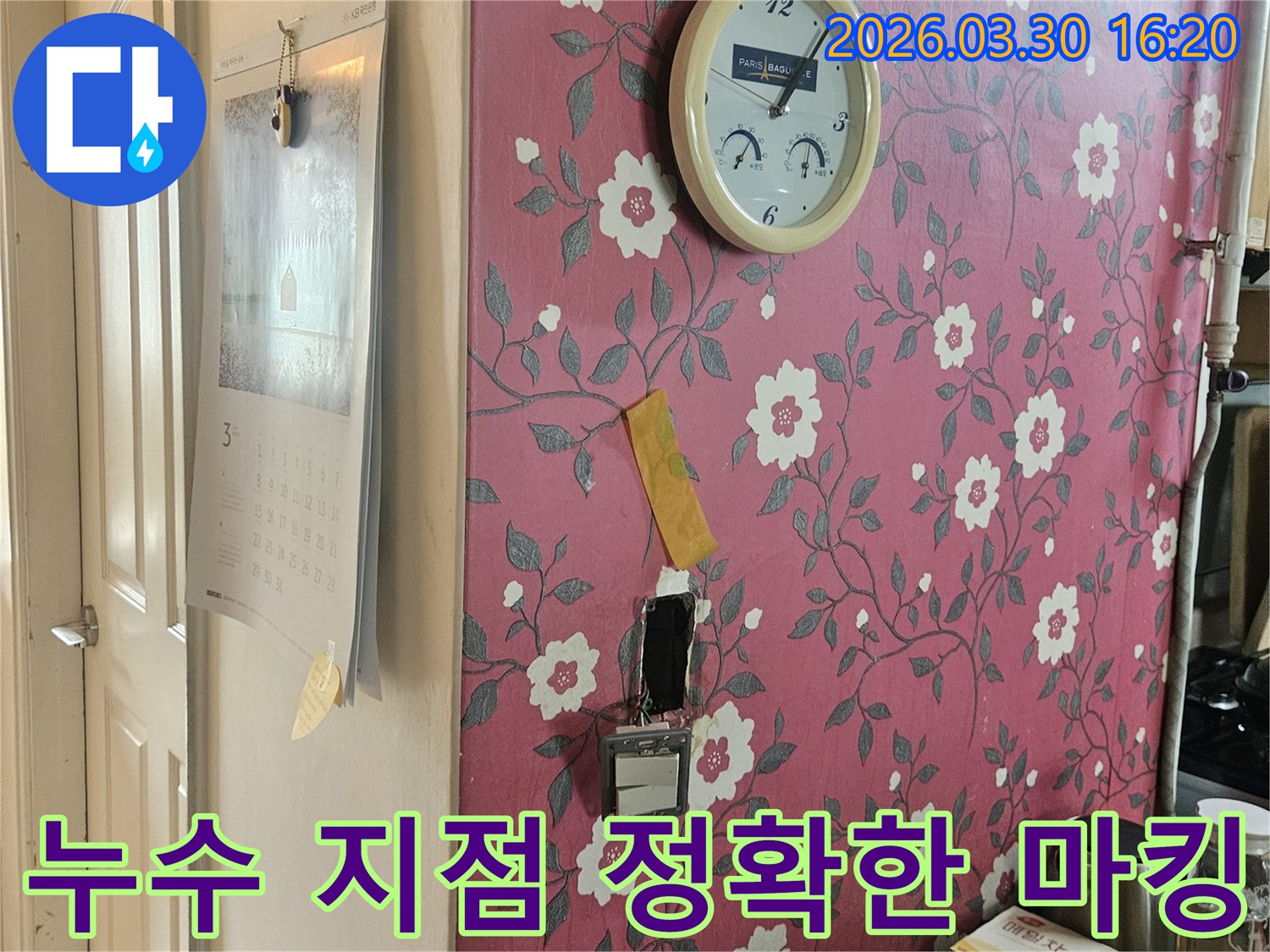 분홍색 꽃무늬 벽지에-시계가-있고-누수-탐지를-위해-개방된-벽면에서-누수-지점을-정확히-마킹하는-사진입니다