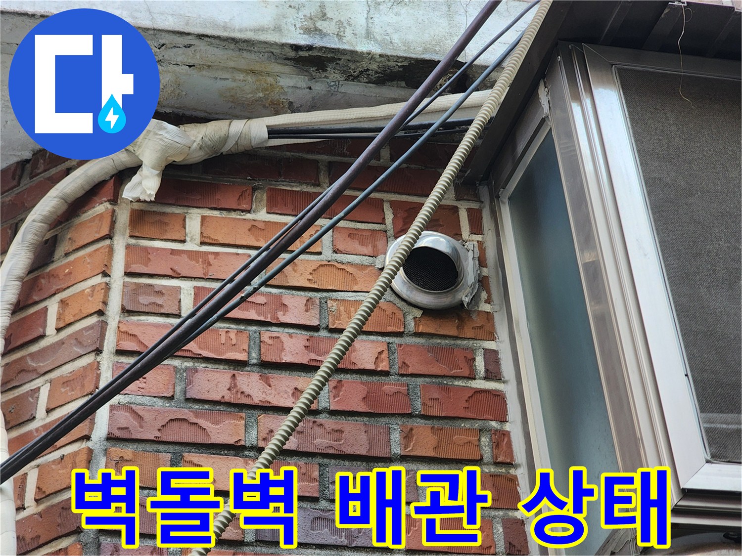 붉은 벽돌 외벽에 설치된 외부 배관과 환기구 모습입니다.
