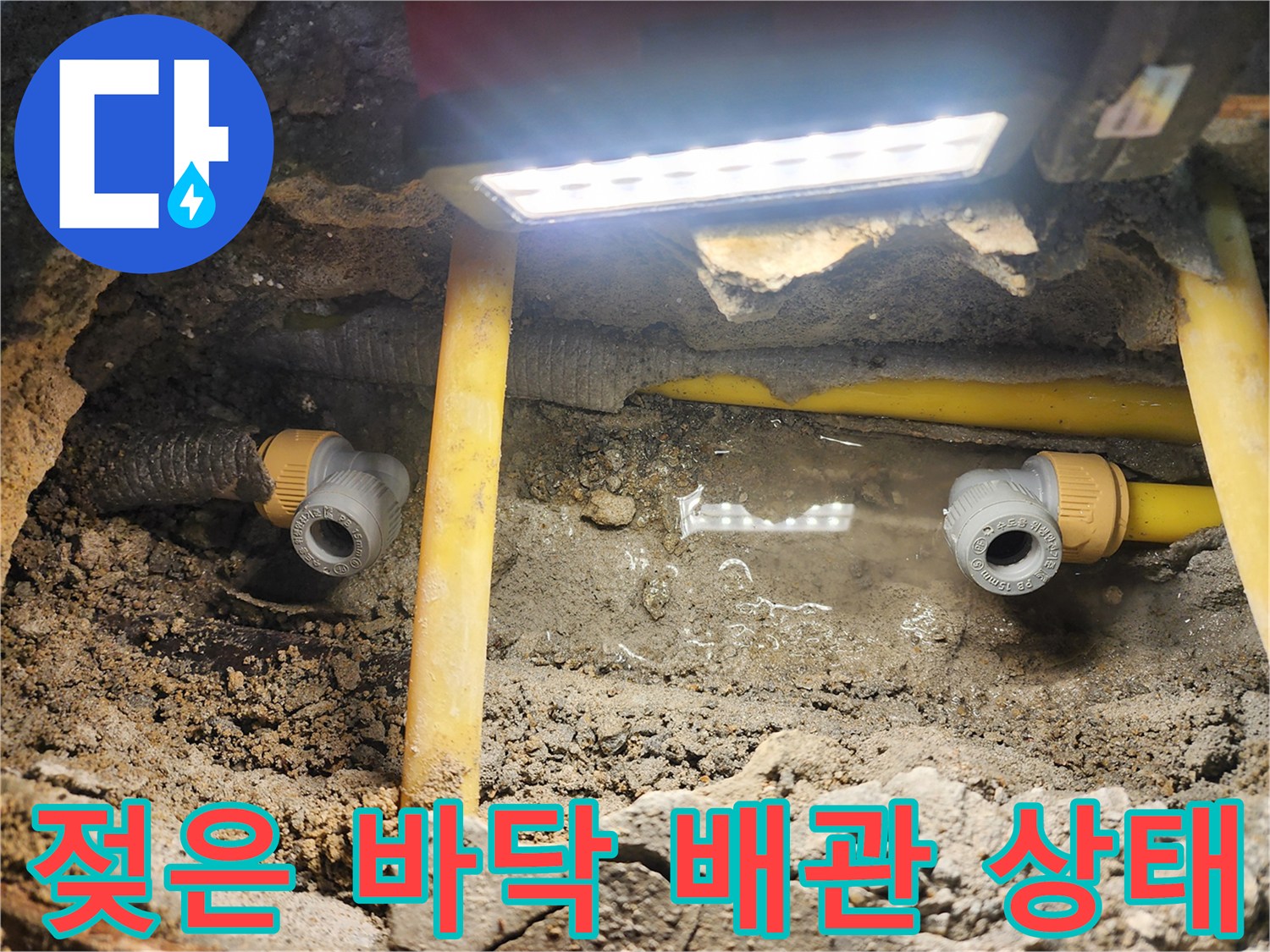 노란색 보호관 주변의 젖은 흙과 고여 있는 물을 촬영한 사진