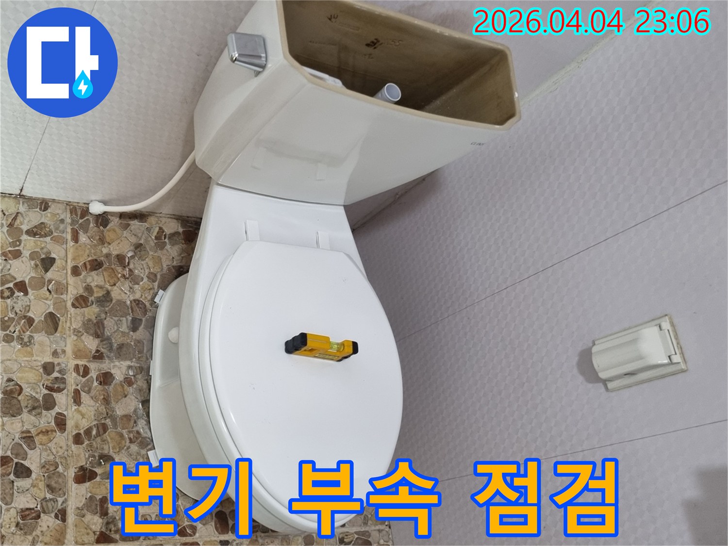 변기 물탱크가 열려 내부 부품이 노출된 상태로-수평계가 변기 시트 위에 놓여-부속 교체를 위한 준비가 되어 있습니다