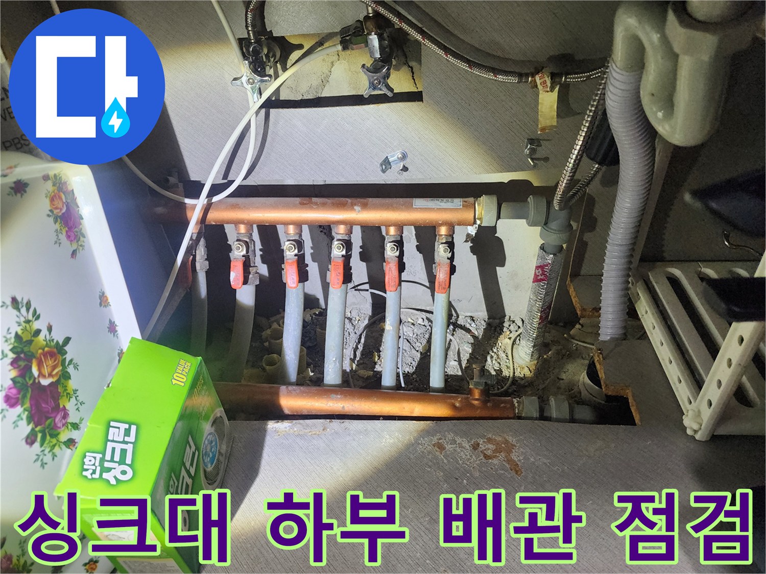 구리 아파트-싱크대 아래 분배기와 구리 배관 상태를 확인하는 모습