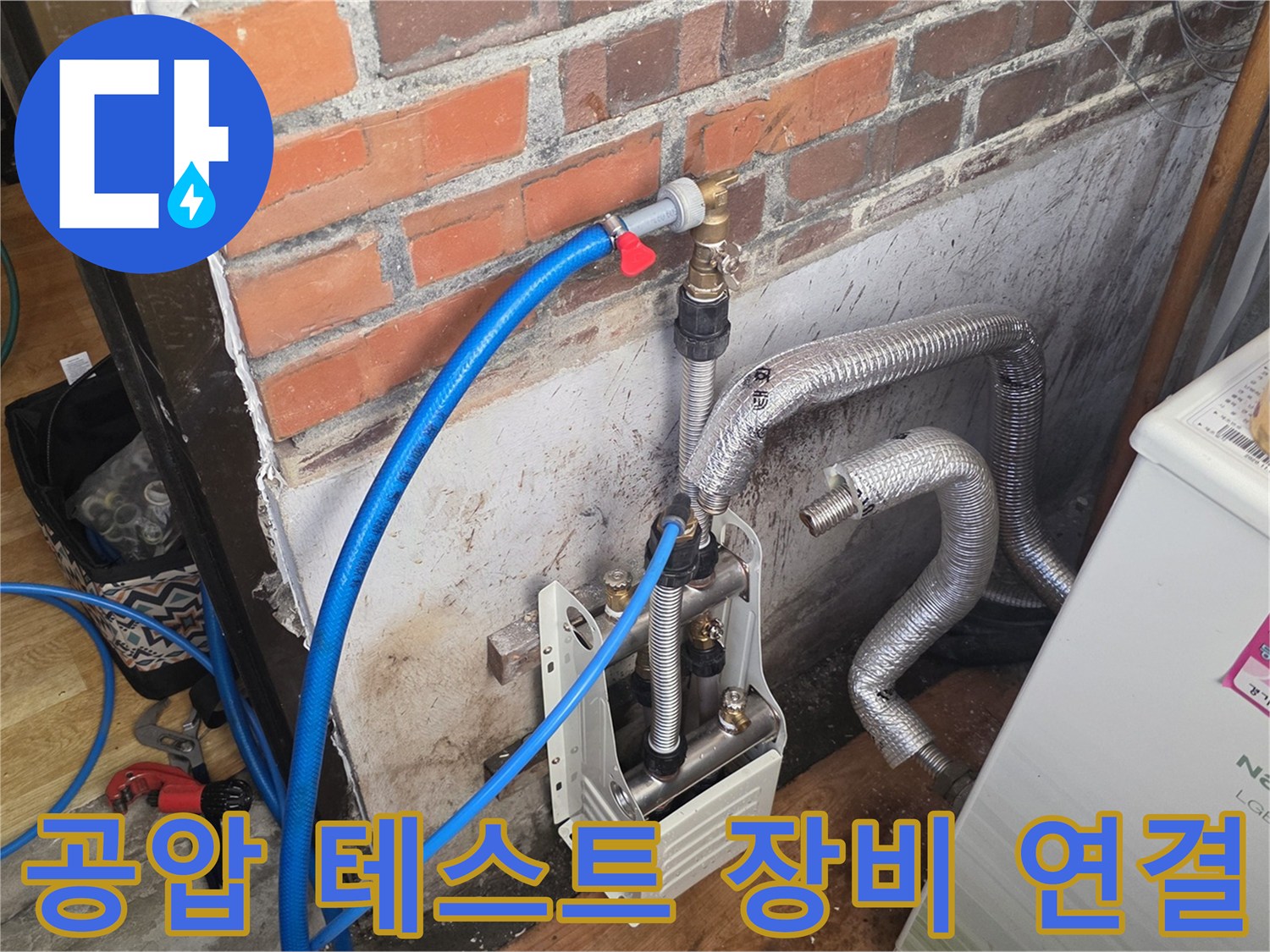 보일러실-벽면-배관에-연결된-파란색-호스와-압력측정-장치