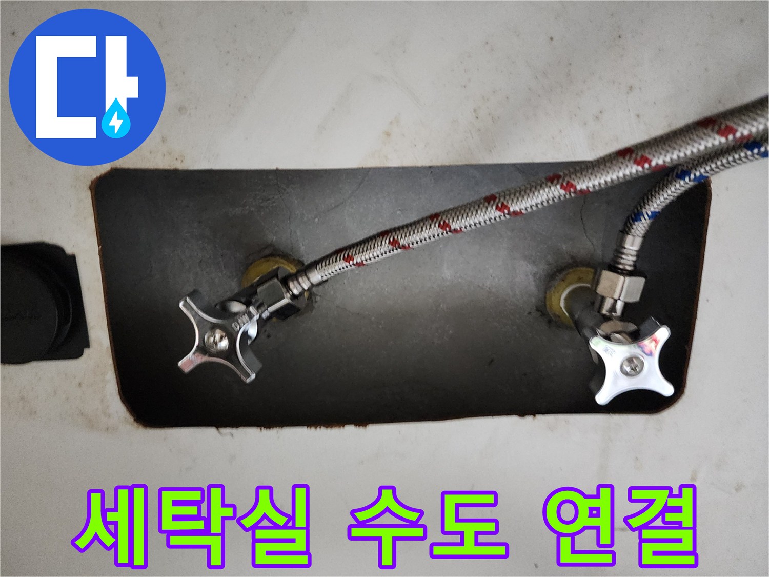 벽면에 고정된 수도 밸브와 금속 호스의 근접 사진