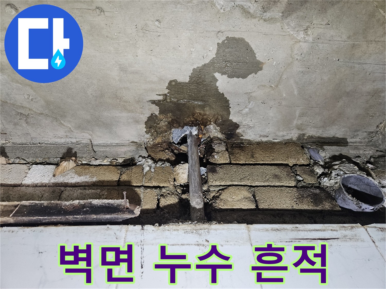 화장실 벽면에 발생한 젖은 얼룩과 노출된 배관 상태