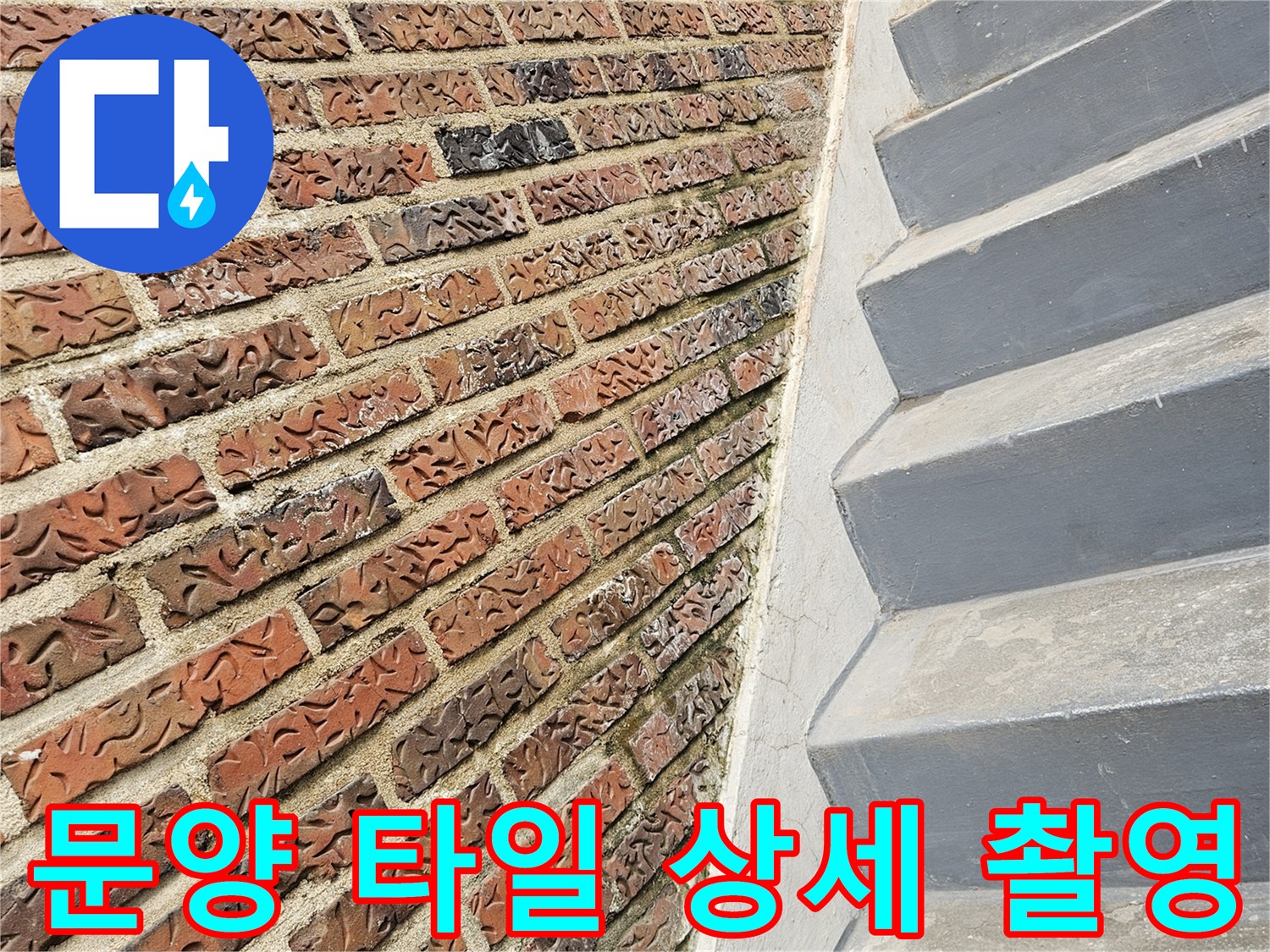 바닥의 붉은색 패턴 타일과 회색 수직 구조물의 경계 부위 사진입니다.