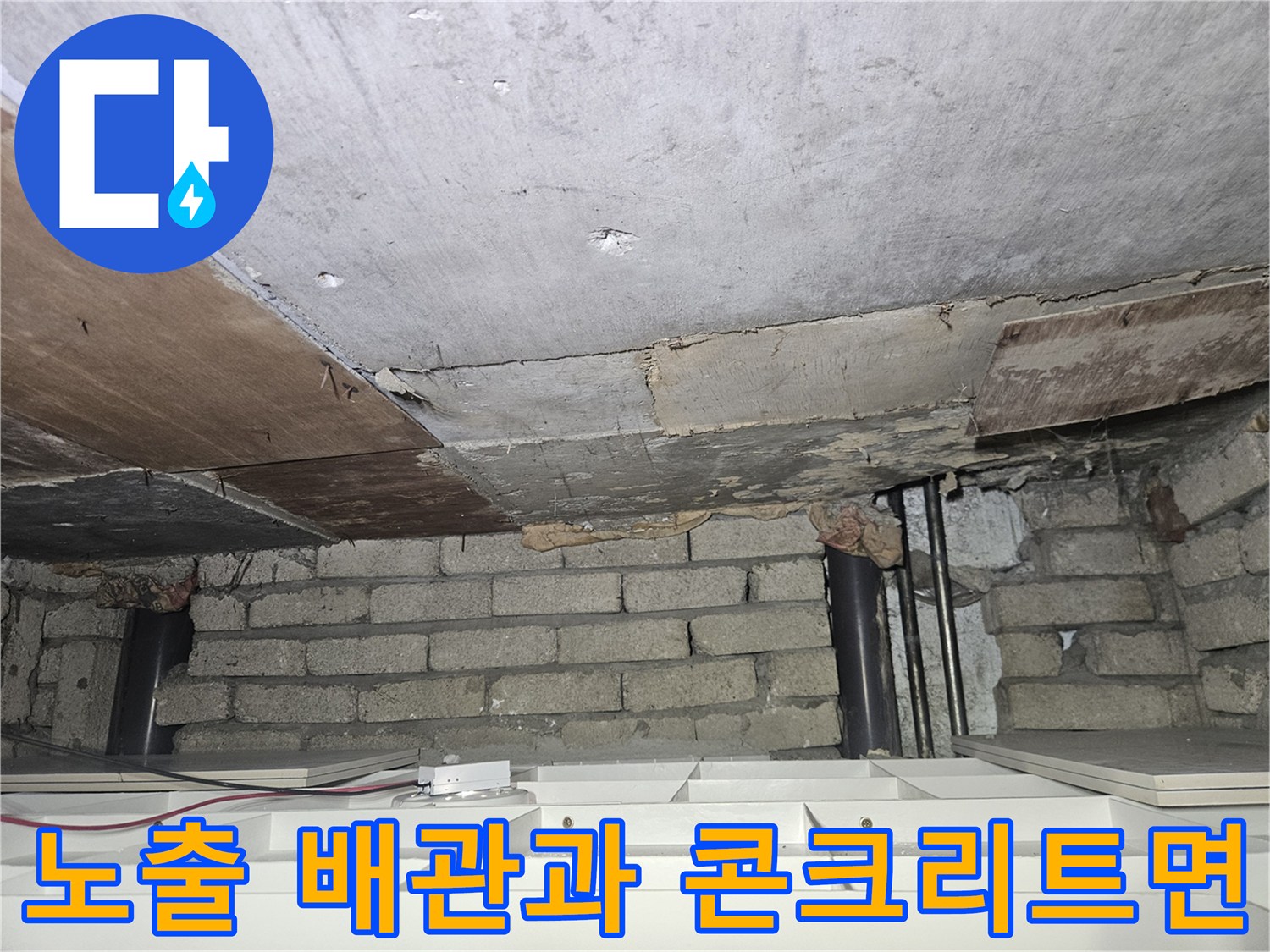 천장 하단-검은색 배관과 노후된 콘크리트 및 목재 구조