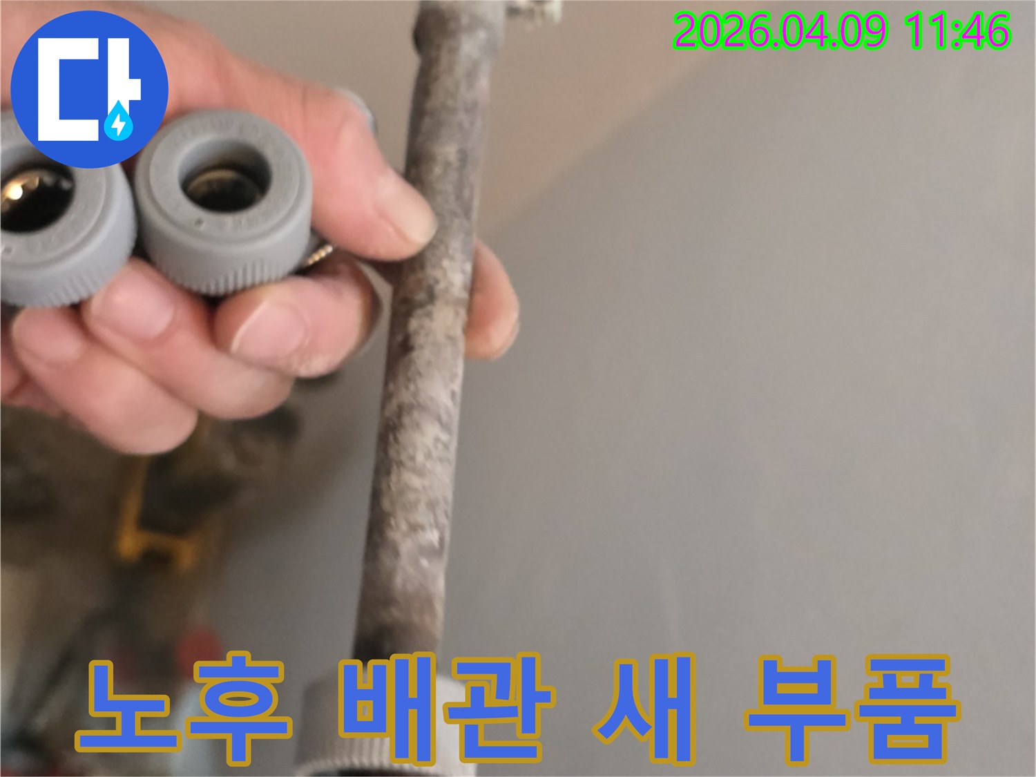 이 사진은-오랜 사용으로 노후된 수도관과-새롭게 교체할 배관 부품을-함께 보여주고 있습니다