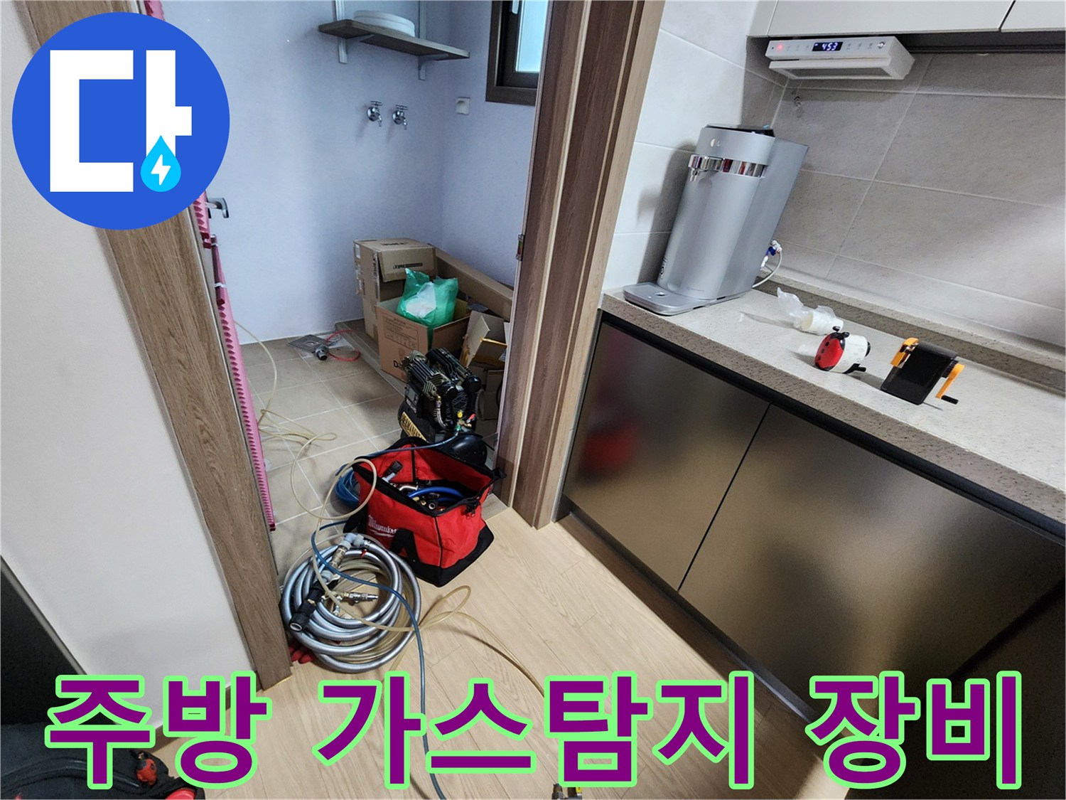 주방 싱크대 하부장 근처에 배치된 가스 탐지기와 배관 점검용 호스들입니다.